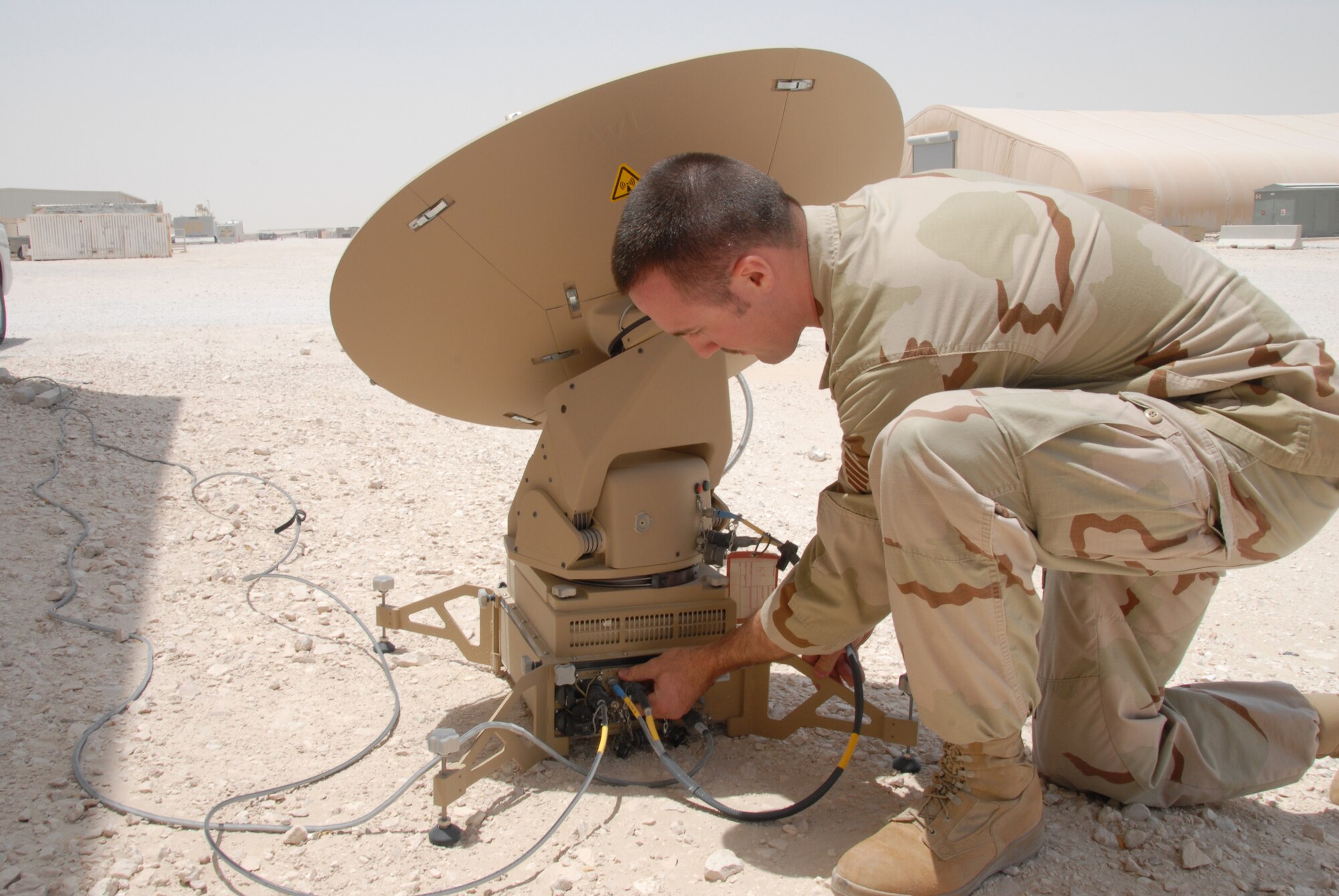 Staff Sgt. Jonathan Salisbury, 379th Expeditionary Civil Engineer Squadron Explosive Ordnance Disposal, checks the input and output cables from a Very Small Aperture Terminal’s satellite dish. (U.S. Air Force photo by Airman 1st Class Ashley Tyler)