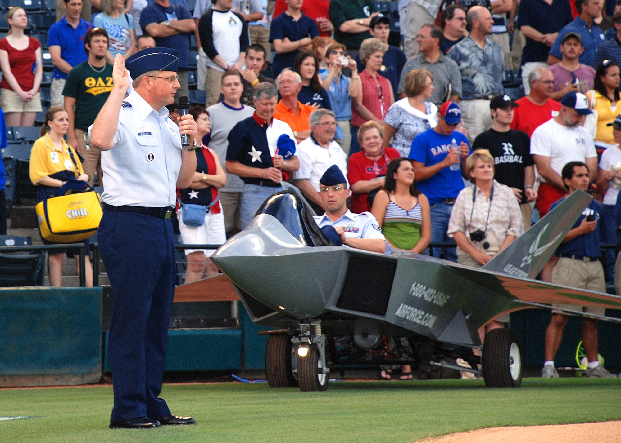 369th Recruiting Group commander, Col. Dan Woolever, administers the oath of enlistment to 120 Delayed Enlistment Program recruits at a July 4th Texas Rangers game, at Ameriquest Stadium near Dallas, Texas. (U.S. Air Force Photo/Master Sgt. Wade Trahan)