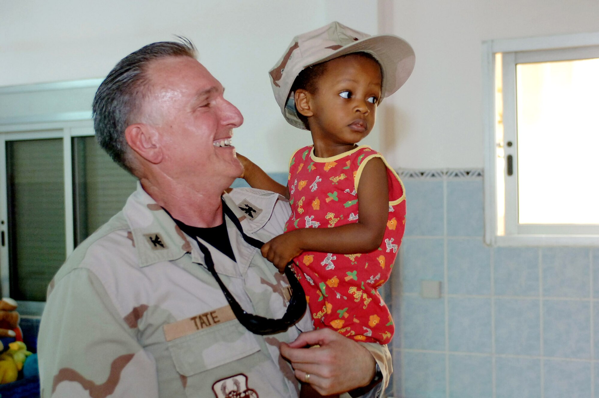 Chaplain (Col.) Gregory Tate surrenders his cover to a child during his July 13 visit to the baby orphanage near Camp Lemonier in Djibouti. Chaplain Tate, the U.S. Central Air Forces Command chaplain, visited Djibouti as part of his Central Command area of operation tour, observing Air Force chaplain services and religious support teams. (U.S. Navy photo/Petty Officer 1st Class John Osborne) 
