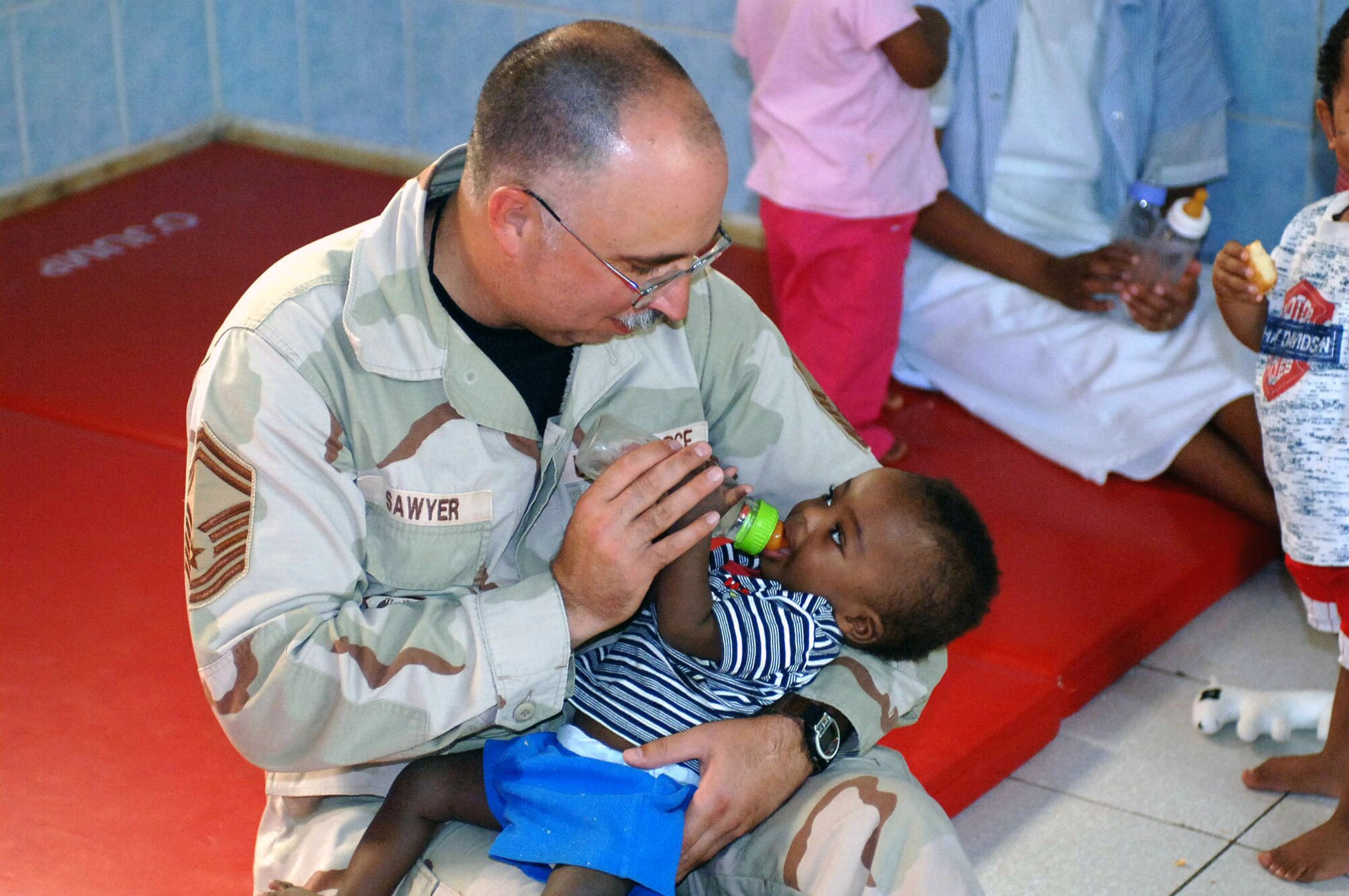Senior Master Sgt. Jeff Sawyer gives a baby a bottle July 12 at the baby orphanage near Camp Lemonier in Djibouti. Sergeant Sawyer is the U.S. Central Air Forces Command chaplain assistant functional manager. He and Chaplain (Col.) Gregory Tate, the CENTAF command chaplain, visited Djibouti as part of his Central Command area of operation tour, observing Air Force chaplain services and religious support teams. (U.S. Navy photo/Perry Officer 1st Class John Osborne)
