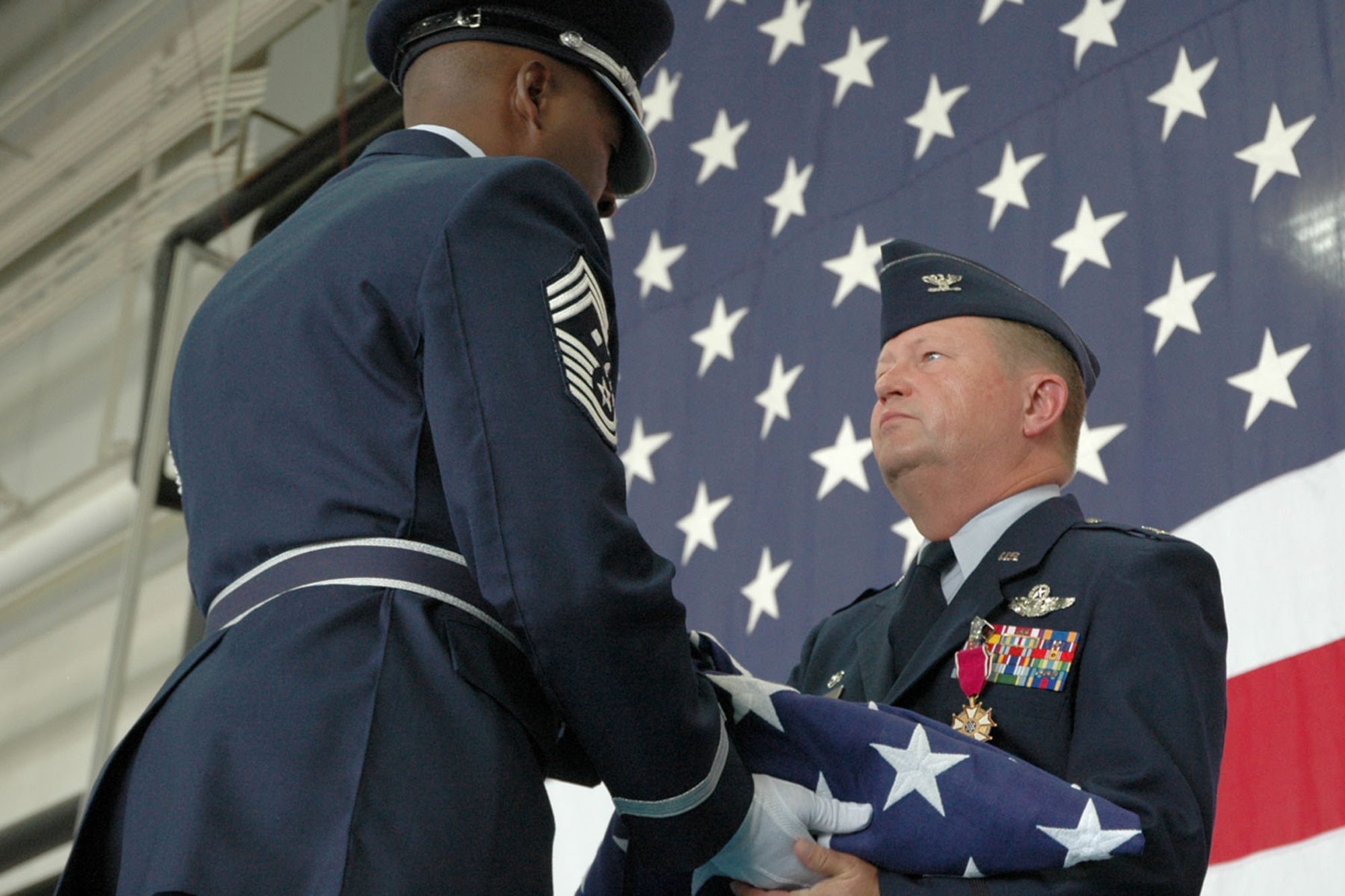 YOUNGSTOWN AIR RESERVE STATION, Ohio - Air Force Reserve Col. Tim Thomson, outgoing commander of the 910th Airlift Wing, accepts a U.S. flag from Chief Master Sgt. Shawn White, a member of the 910th Airlift Wing's Honor Guard. The flag was presented to Col. Thomson on the occasion of his retirement ceremony after 34 years of service to the Air Force. The ceremony, attended by wing personnel, family and friends, was held here July 15 following a change of command ceremony for the 910th Airlift Wing. Col. Thomson was succeeded by Col. Karl McGregor, who comes to Youngstown after his most recent assignment as operations group commander of the 439th Airlfit Wing, Westover Air Reserve Base, Mass. U.S. Air Force photo/Tech. Sgt. Bob Barko Jr.  