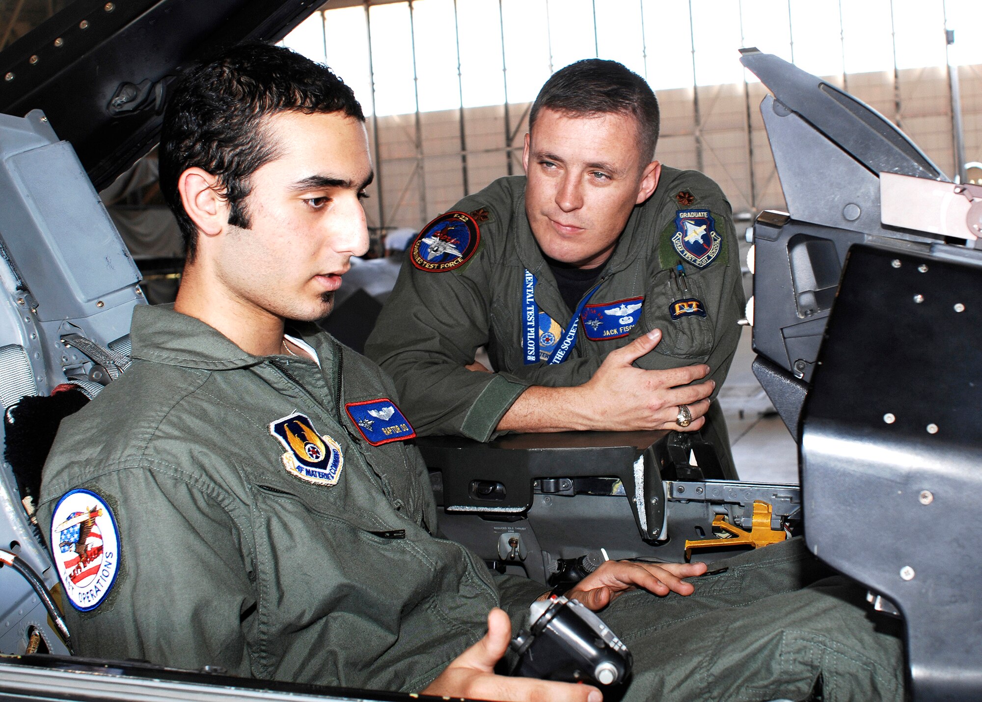 Maj. Jack Fischer (right), 411th Flight Test Squadron F-22 Raptor pilot, explains the different controls in an F-16 Fighting Falcon cockpit to Avi Khanian (left) during the "Pilot for a Day" tour here July 12. As a pilot for the day, 14-year-old Avi received an opportunity to see Edwards' various aircraft including the CV-22, F-22A, F-16 and the Global Hawk. The program was sponsored by the base's Company Grade Officer Council. Avi has undergone treatment at Mattel Children's Hospital in Los Angeles for Ewing's sarcoma, a form of bone cancer often found in children. (Photo by Jim Shryne)