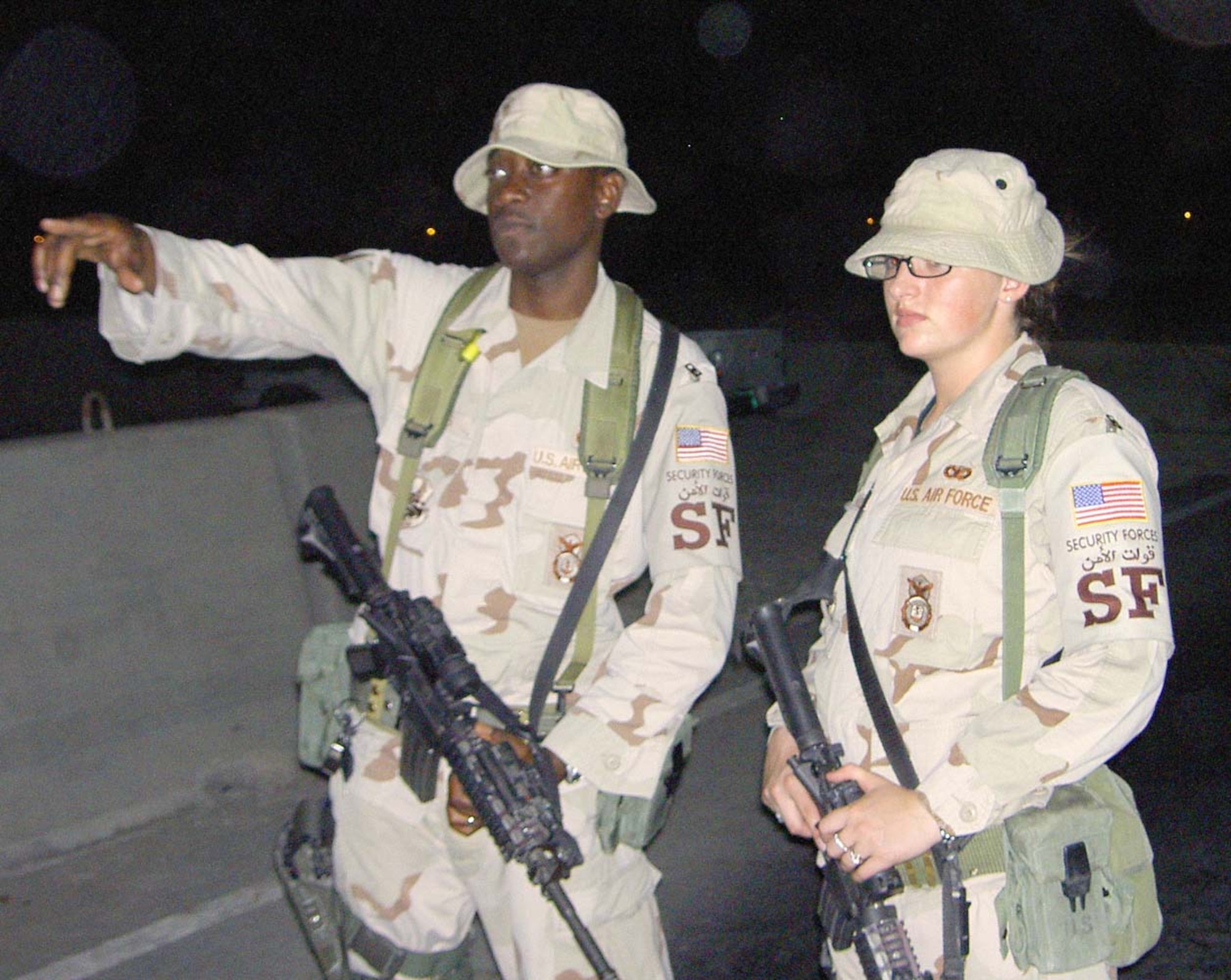 Staff Sgt. Ronnie Titus and Airman 1st Class Amy Kukal, both of the 14th Security Forces Squadron, identify an approaching vehicle while on gate guard duty during their deployment. They are part of a team that not only stand guard at the various points across the wing but is also searchs every vehicle prior to be granted access to the base. (U.S. Air Force Photo by Master Sgt. Allen Rigdon)
