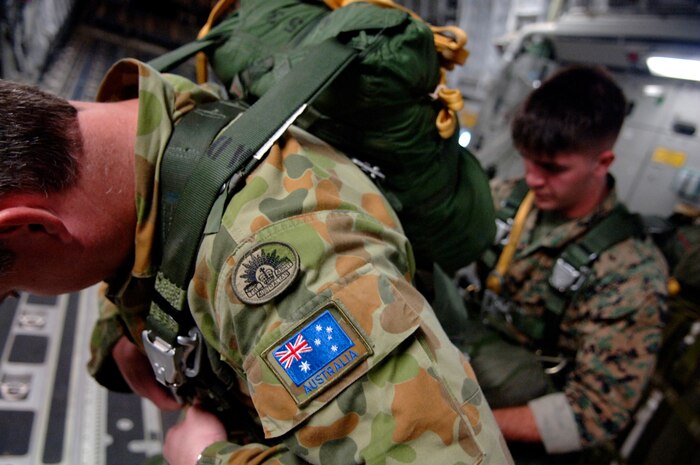U.S. Marine Corps Cpl. John Powell, a parachute rigger in the 2nd Air Delivery Unit out of Camp Lejeune, N.C., helps Australian Army Warrant Officer Class Two Adrian South, project officer for aerial delivery systems air movements, training and developments unit, don his parachute for a joint service airdrop training exercise July 12, 2007 at Charleston AFB, S.C. (U.S. Air Force Photo/Airman 1st Class Nicholas Pilch)