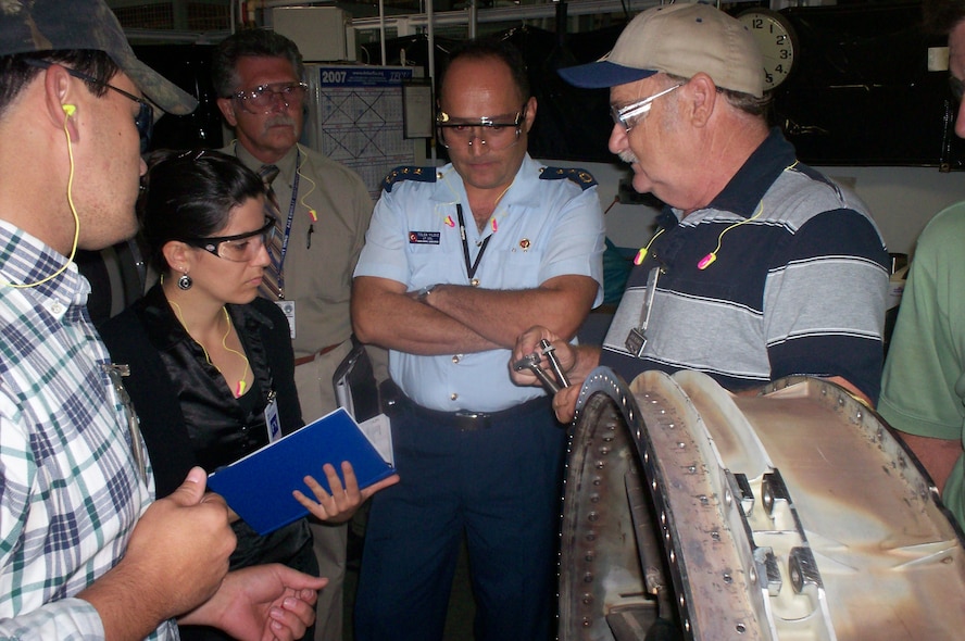 Jack McSwain, 548th Propulsion Maintenance Squadron welding supervisor, explains the oil tube welding process to Turkish welding engineer Burcu Okur during a visit July 9 and 10. Looking on are, from left, Darren Raines, 548th PMXS welder; Larry Waite, Turkish program manager with the 748th Combat Sustainment Group; and Lt. Col. Tolga Yidiz, Turkish air force liaison. (Air Force photo by 2nd Lt. Eric Scott)

