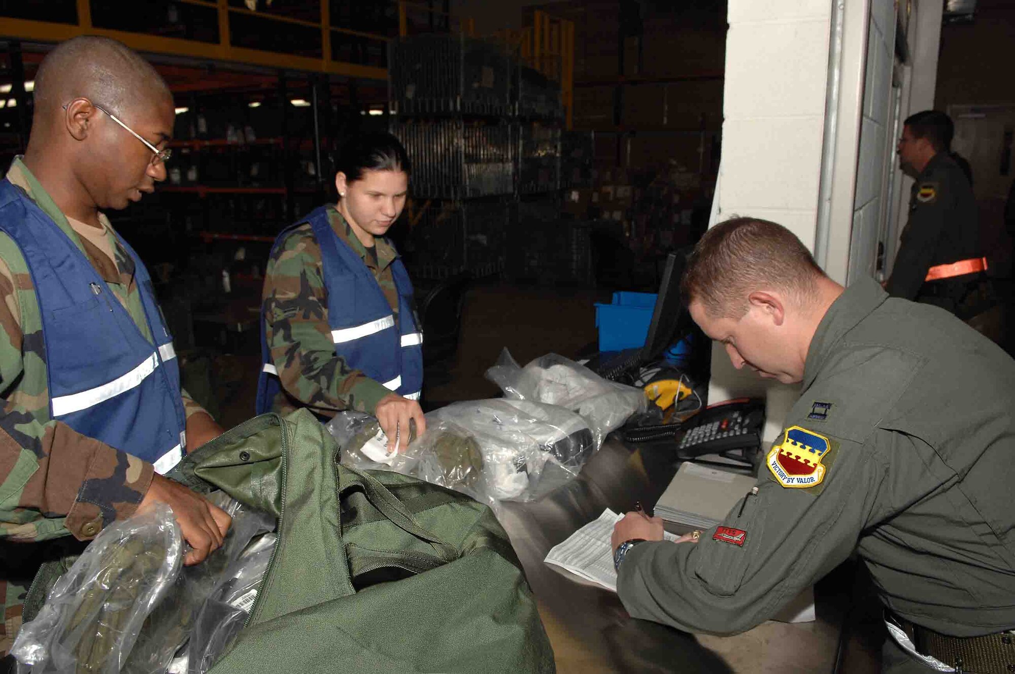 SHAW AIR FORCE BASE, S.C.-- Staff Sgt. Michael Henry, 20th Communications Squadron project manager, and Airman 1st Class Elizabeth Mclean, 20th Services Squadron food services technician, issue chemical warfare gear to Capt. Daniel McAffe, 77th Fighter Squadron, during a Phase I operational readiness exercise at the Chandler Deployment Processing Center July 16.  Operational readiness exercises are a training tool to help prepare Airmen for pre-deployment and deployment mission requirements. (U.S. Air Force Photo/Staff Sgt. Henry L Hoegen Jr.)