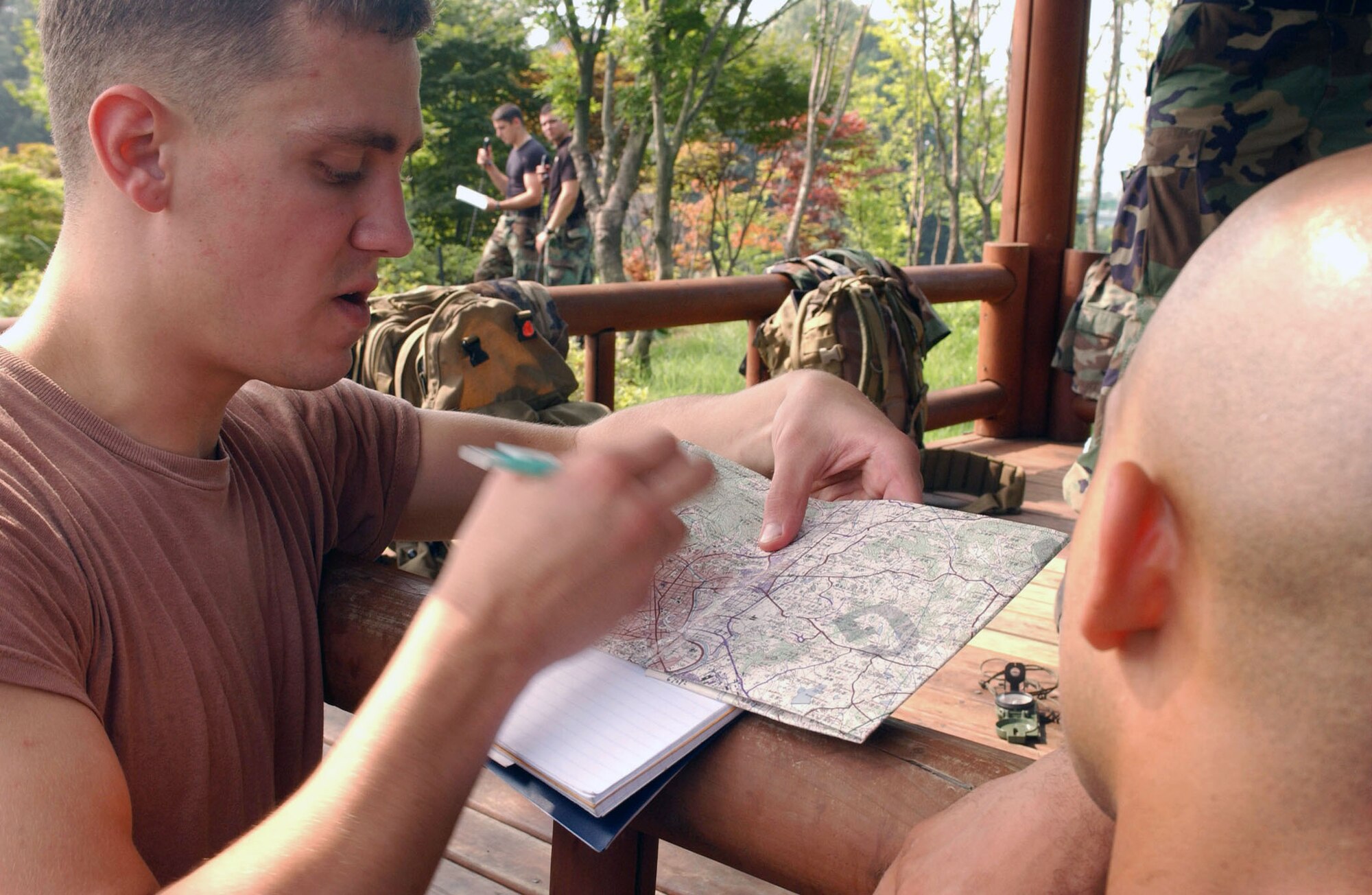 Senior Airman Kevin Rosner teaches Staff Sgt. Vincent Reed how to interpret a map as tactical air controllers call in simulated air support missions behind them July 12 in Jeonju, South Korea. Airman Rosner is a joint terminal attack controller trainer from Army Garrison Casey. The JTACs, assigned to the 604th Air Support Operations Squadron at the same Army location, teamed with pilots from both the 35th and 80th Fighter Squadrons, based at Kunsan Air Base, South Korea, to hone their abilities to perform close-air support missions. Sergeant Vincent is assigned to the 8th Security Forces Squadron. (U.S. Air Force photo/Senior Airman Steven R. Doty) 
