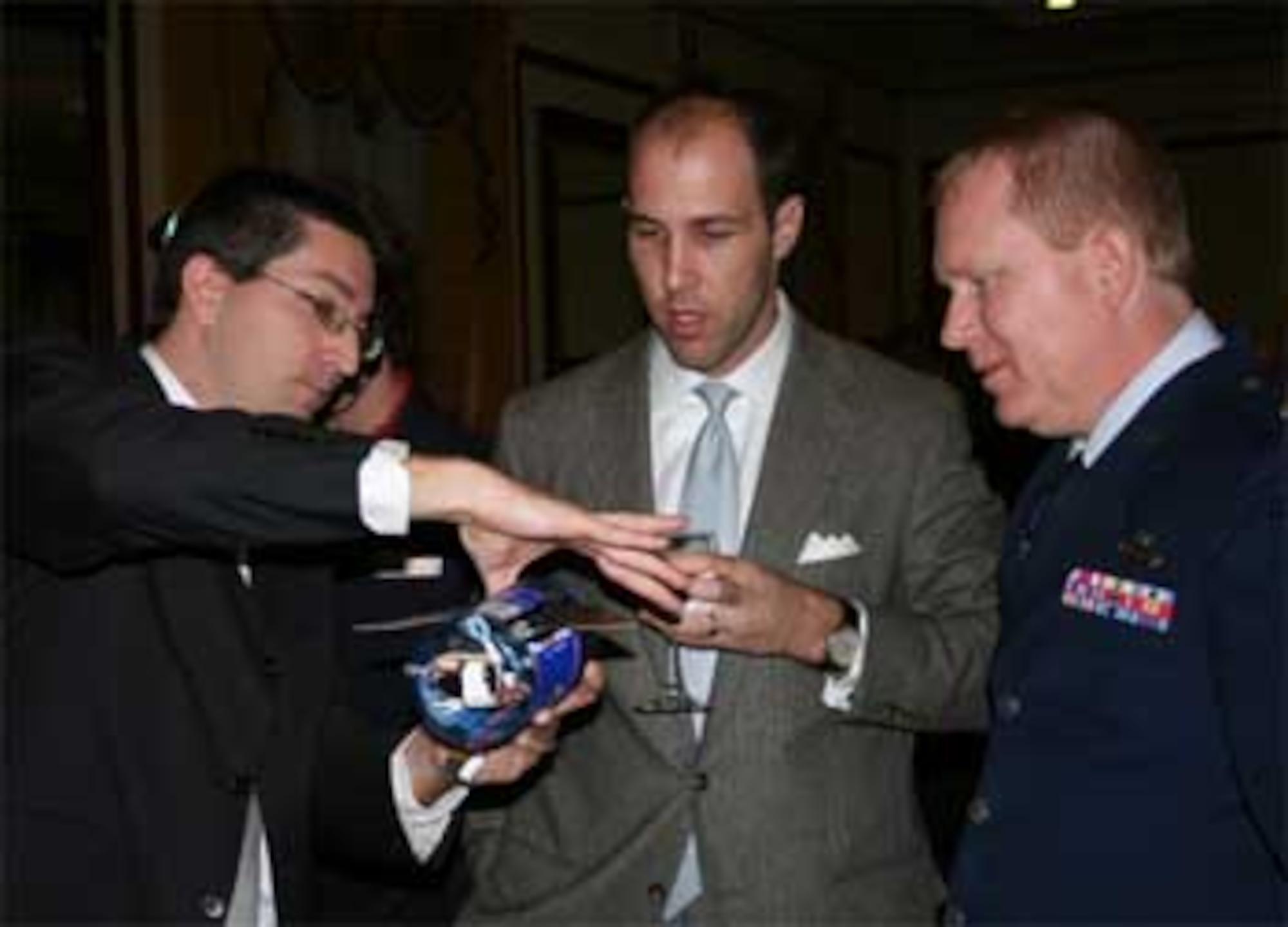 Dr. Rick Lind, left, uses a model to explain his UAV research to Andrew Kauders, center, and Lt. Col. Scott R. Wells. Lind is an assistant professor at the University of Florida. Kauders in a principal with the Podesta Group in D.C. Wells is one of several AF