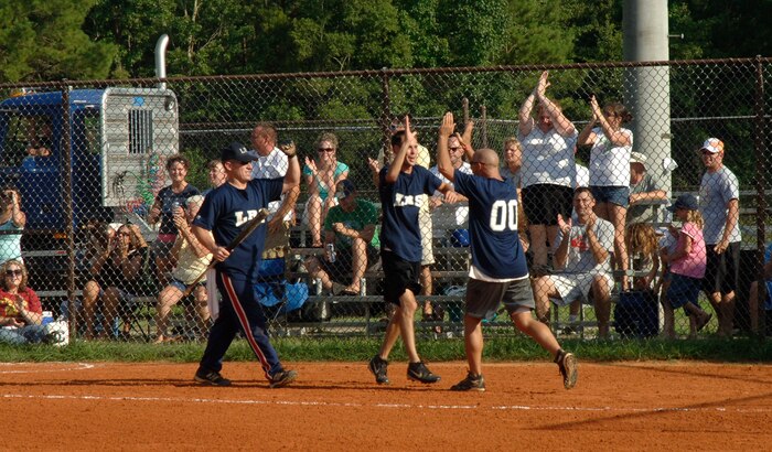Jason Maine, Matt Sexton and Todd Robb, 437 LRS, and fans celebrate the second ball that was knocked out of the park which brought in two runners for their team.(U.S. Air Force Photo/Staff Sgt. April Quintanilla)