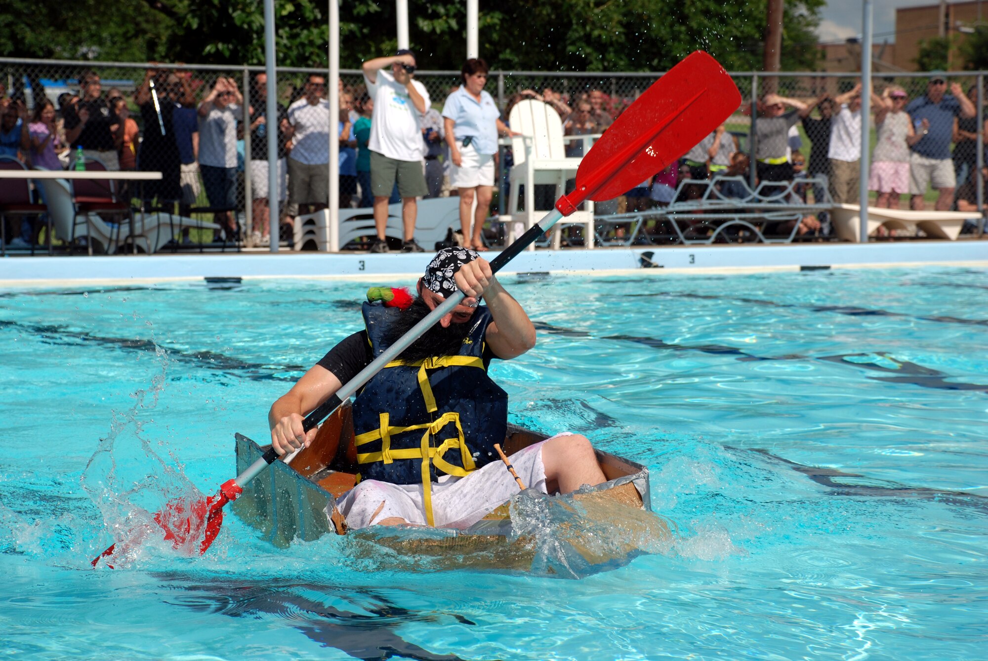 Airman Matthew Turco, an Airman-in-Training with the 360th Training Squadron and member of the Nasty Pirates boat race team, paddles furiously during the annual Build-a-Boat Race July 14 at the main pool. (U.S. Air Force photo/Airman 1st Class Jacob Corbin)
