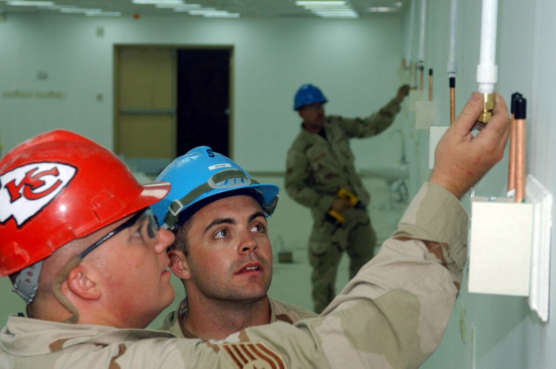 BALAD AIR BASE, Iraq -- Tech. Sgt. Tyson Hillis, a biomedical equipment technician and transition team lead here with the 332nd Expeditionary Medical Group's Expeditionary Medical Support Squadron, teaches Senior Airman Scott Hatch, 332nd MDG MDSS transition team member, on how the new vacuum system will be connected from the ceiling to the wall boxes in the new Air Force Theater Hospital. Sergeant Hillis, deployed from the 382nd Training Squadron at Sheppard Air Force Base, Texas, and Airman Hatch, deployed from the 81st MDSS at Keesler AFB, Miss., are part of a seven-man transition team focused on the installation and continual maintenance of the various medical equipment used in the current tent city hospital and the new, pre-engineered facility. (U.S. Air Force photo by 1st Lt. Shannon Collins)                                      