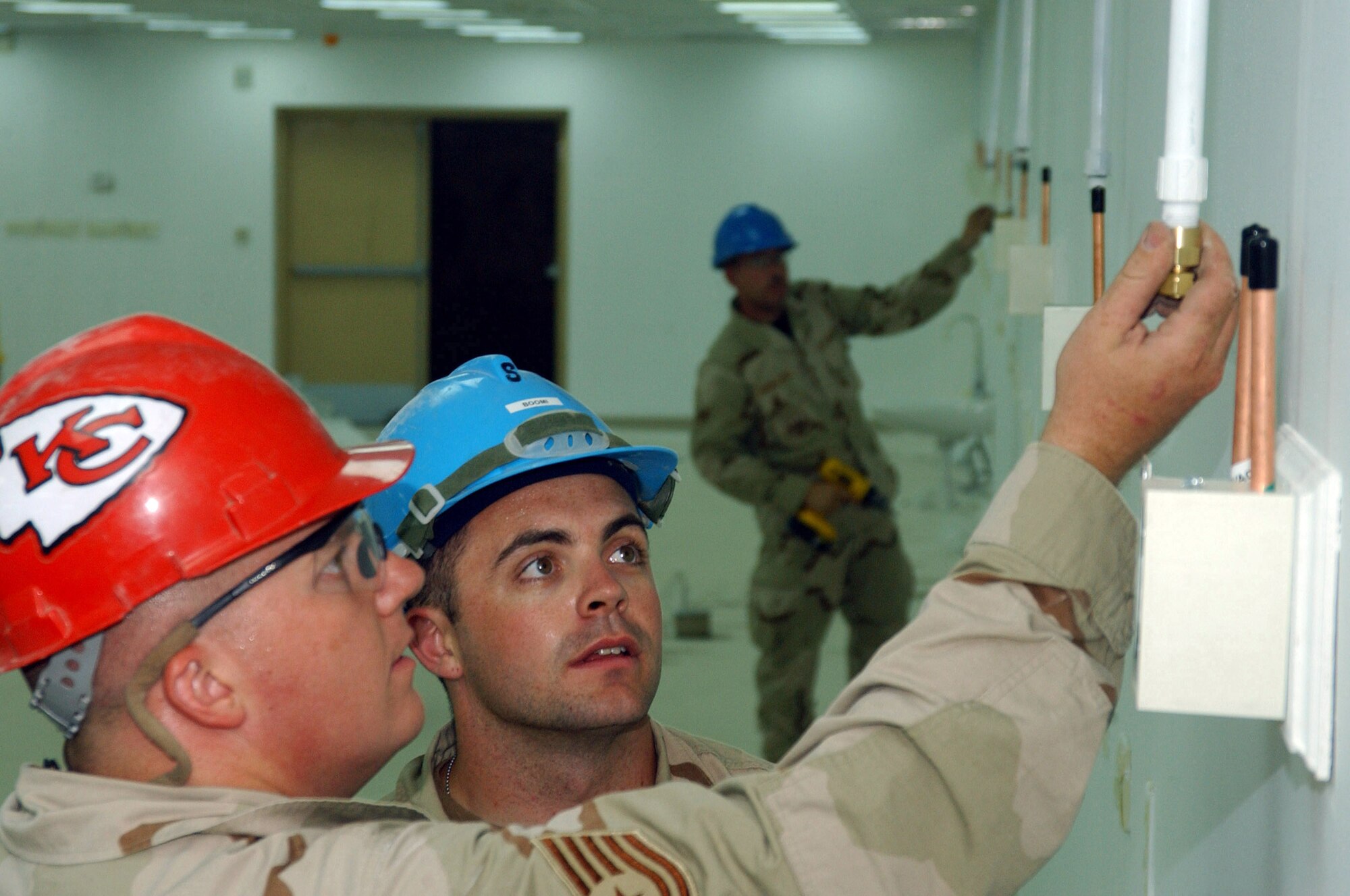 BALAD AIR BASE, Iraq -- Tech. Sgt. Tyson Hillis, a biomedical equipment technician and transition team lead here with the 332nd Expeditionary Medical Group's Expeditionary Medical Support Squadron, teaches Senior Airman Scott Hatch, 332nd MDG MDSS transition team member, on how the new vacuum system will be connected from the ceiling to the wall boxes in the new Air Force Theater Hospital. Sergeant Hillis, deployed from the 382nd Training Squadron at Sheppard Air Force Base, Texas, and Airman Hatch, deployed from the 81st MDSS at Keesler AFB, Miss., are part of a seven-man transition team focused on the installation and continual maintenance of the various medical equipment used in the current tent city hospital and the new, pre-engineered facility. (U.S. Air Force photo by 1st Lt. Shannon Collins)                                      