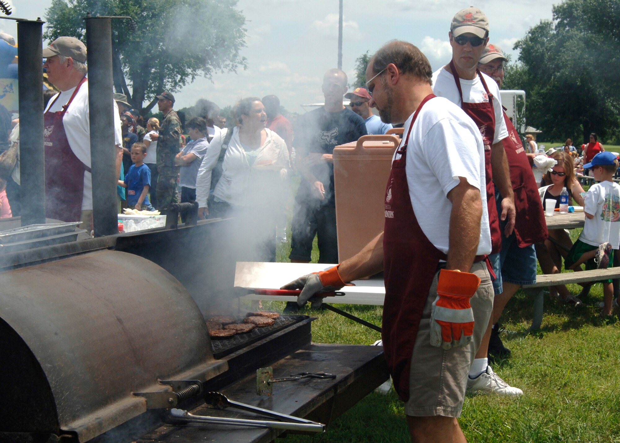 MCCONNELL AIR FORCE BASE, Kan. -- Todd Woodburn, a Wichita Wagonmasters member, flips hamburgers during the McConnell Open House picnic July 13 at the Robert J. Dole Community Center. Members of the Wichita Wagonmasters, a local, civic group, cooked food for McConnell members during the picnic. The base held the picnic to honor military members and their families. Approximately 1,800 people attended the event. The picnic featured several aerial demonstrations including performances from the F-16 Viper West Team, the Navy Blue Angels, and the Army Golden Knights. (Photo by Airman 1st Class Roy Lynch)