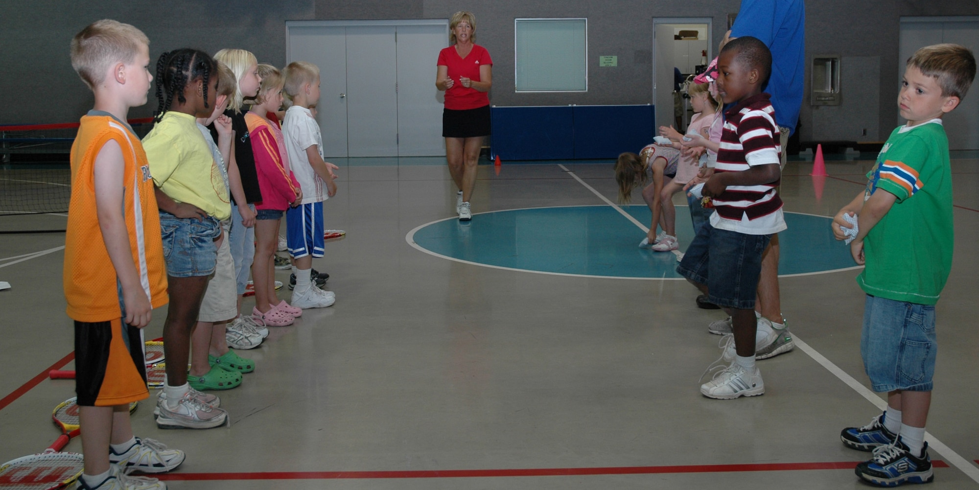 Little Warriors eagerly await the chance to pick up their rackets and start practicing tennis moves while instructor Kim Herremans explains the rules.  (U.S. Air Force photo / Airman 1st Class Dillon White)