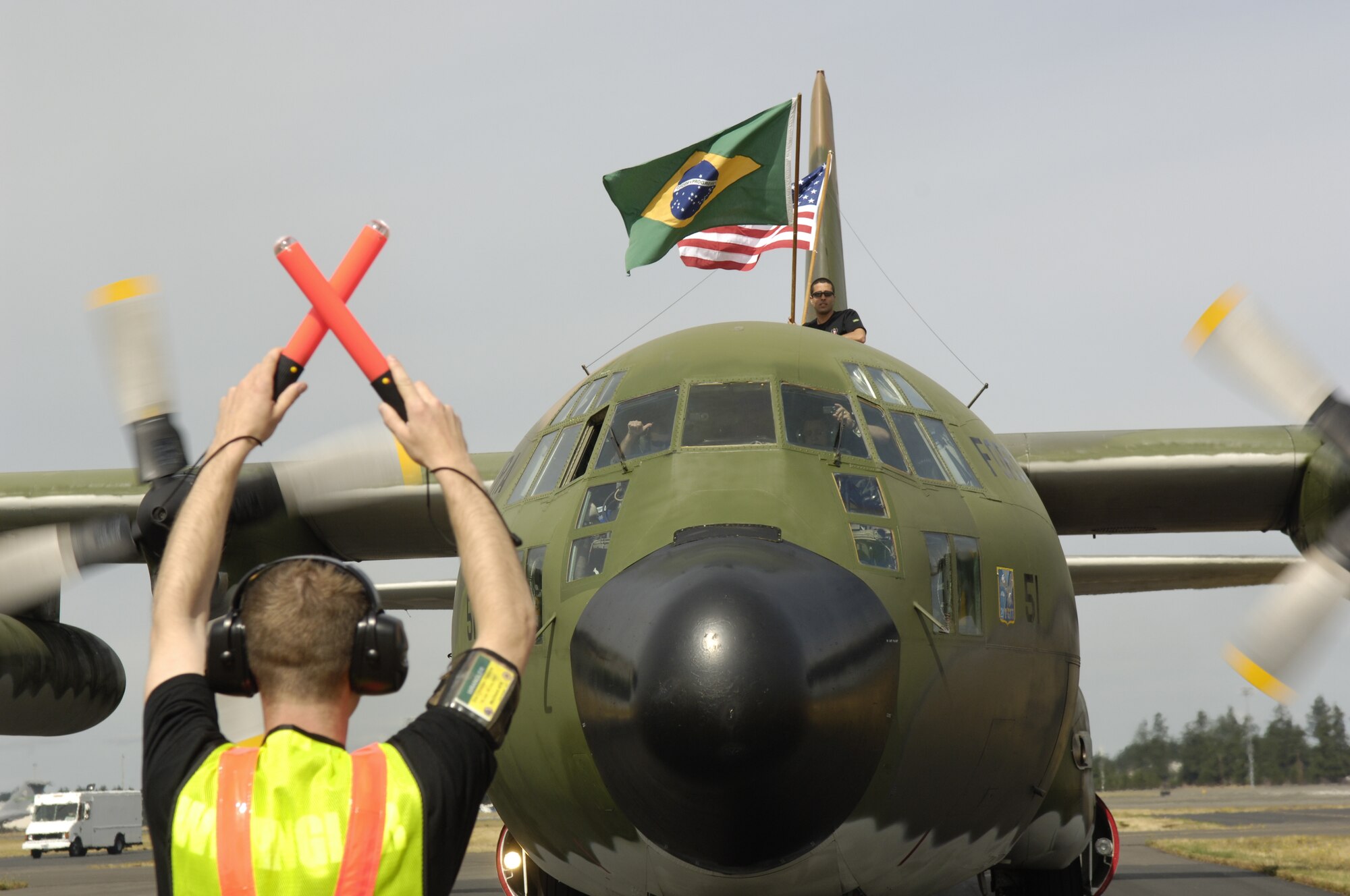 A Rodeo "Wrangler" marshalls a Brazilian C-130 Hercules aircraft to its parking space for Rodeo 2007 at McChord Air Force Base, Wash., on July 16. Air Mobility Rodeo 2007, hosted by Air Mobility Command, is a readiness competition of U.S. and international mobility air forces. It focuses on improving warfighting capabilities and support of the Global War on Terrorism. (U.S. Air Force Photo by Tech. Sgt. Maria J. Bare)