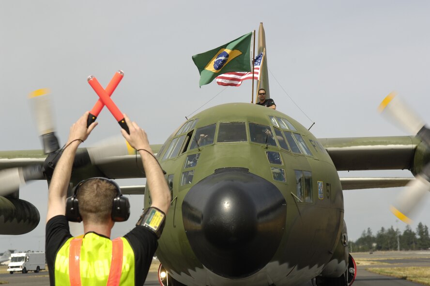 A Rodeo "Wrangler" marshalls a Brazilian C-130 Hercules aircraft to its parking space for Rodeo 2007 at McChord Air Force Base, Wash., on July 16. Air Mobility Rodeo 2007, hosted by Air Mobility Command, is a readiness competition of U.S. and international mobility air forces. It focuses on improving warfighting capabilities and support of the Global War on Terrorism. (U.S. Air Force Photo by Tech. Sgt. Maria J. Bare)
