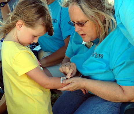 Youth Center employee Brenda Stevens applies a “tattoo” to one of Malmstrom’s Little Warriors at last year’s base picnic.
