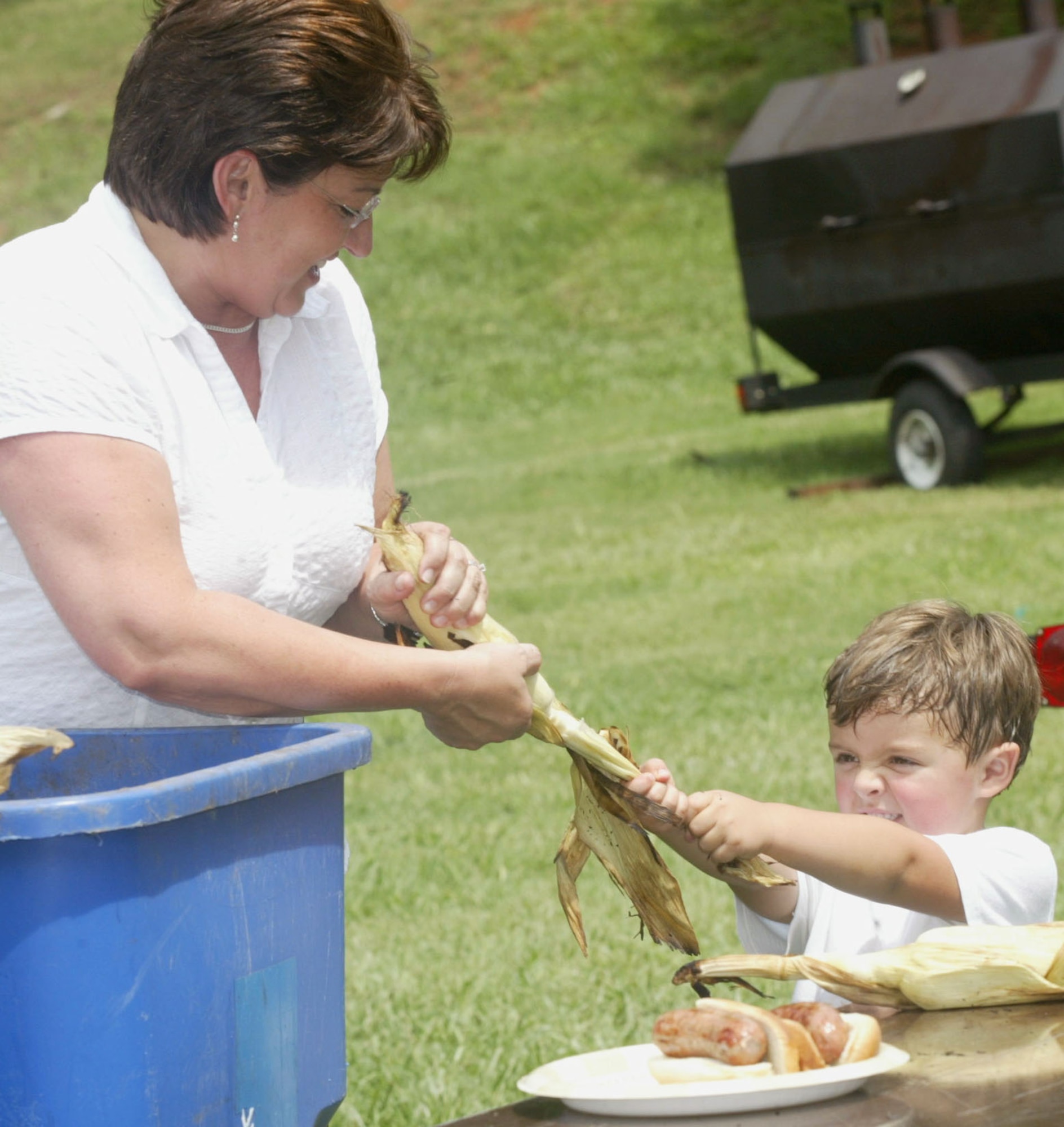 A young attendee of the annual Corn and Sausage Roast at Dobbins Air Reserve Base, Ga., has a little trouble with his shucking. The event, put on by the Dobbins Square and Compass Club and manned with volunteers from the Chiefs Group and Family Support, raised more than $2,000 for Family Support's emergency funds. More than 400 ears of grilled corn were consumed. (U.S. Air Force photo/Don Peek)