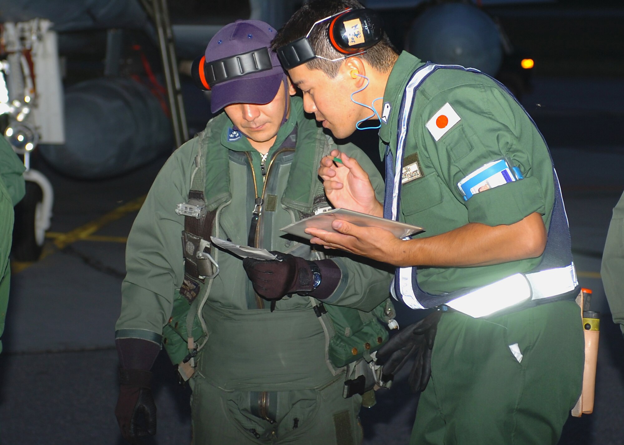 A pilot from the Japan Air-Self Defense Force (left) confers with a maintenance specialist after arriving from Hyukari Air Base near Tokyo for Red Flag-Alaska, an air combat training exercise over the Pacific Alaskan Range Complex.