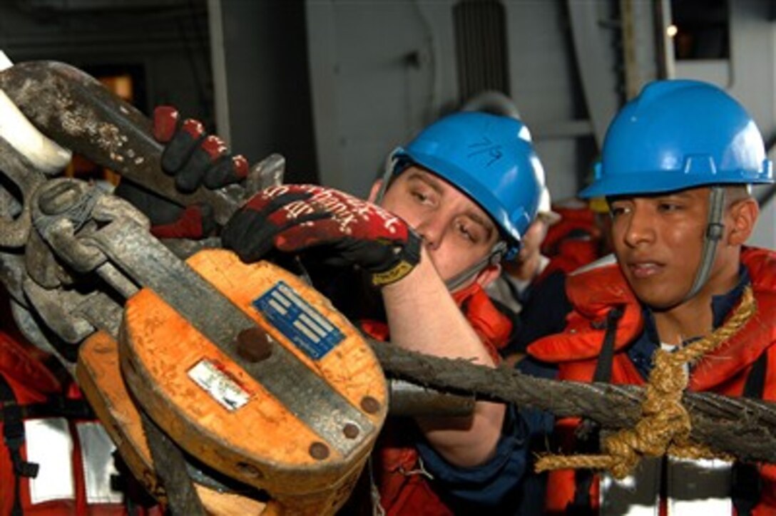 U.S. Navy Boatswain's Mate 3rd Class Roger Silva (right) supervises as Boatswain's Mate 3rd Class Kyle Coffrin hooks up the high line during an underway replenishment in the hangar bay aboard the Nimitz-class aircraft carrier USS Harry S. Truman (CVN 75) in the Atlantic Ocean on July 17, 2007.  The Truman is participating in a composite training unit exercise in preparation for deployment.  