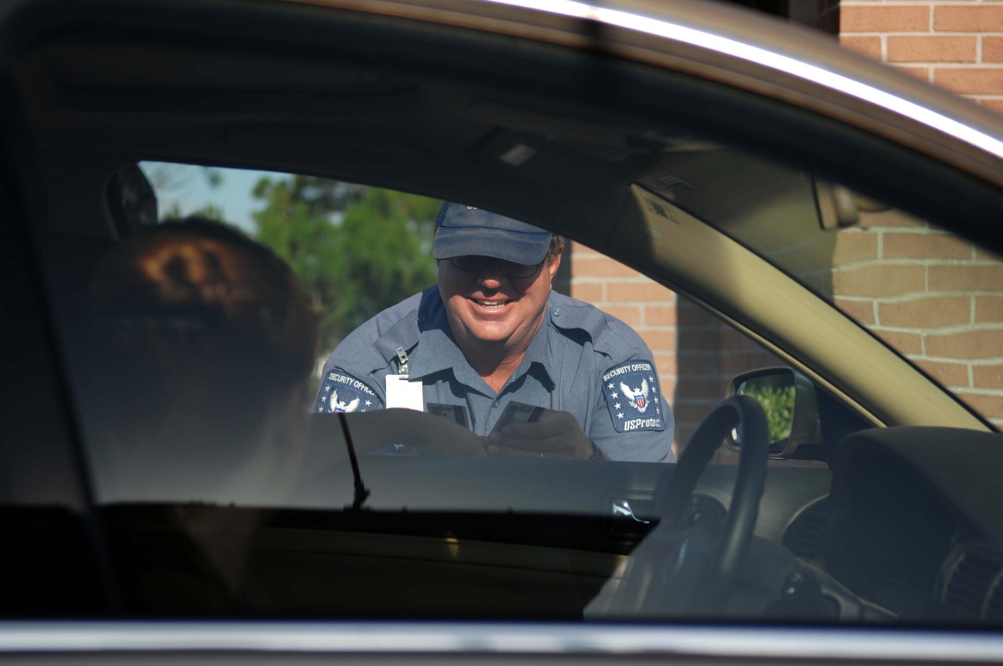 USProtect guard William Alford greets a civilian at the front gate and checks her identification. Mr. Alford is known for his trademark greeting. Photo by Senior Airman Andy Kin.