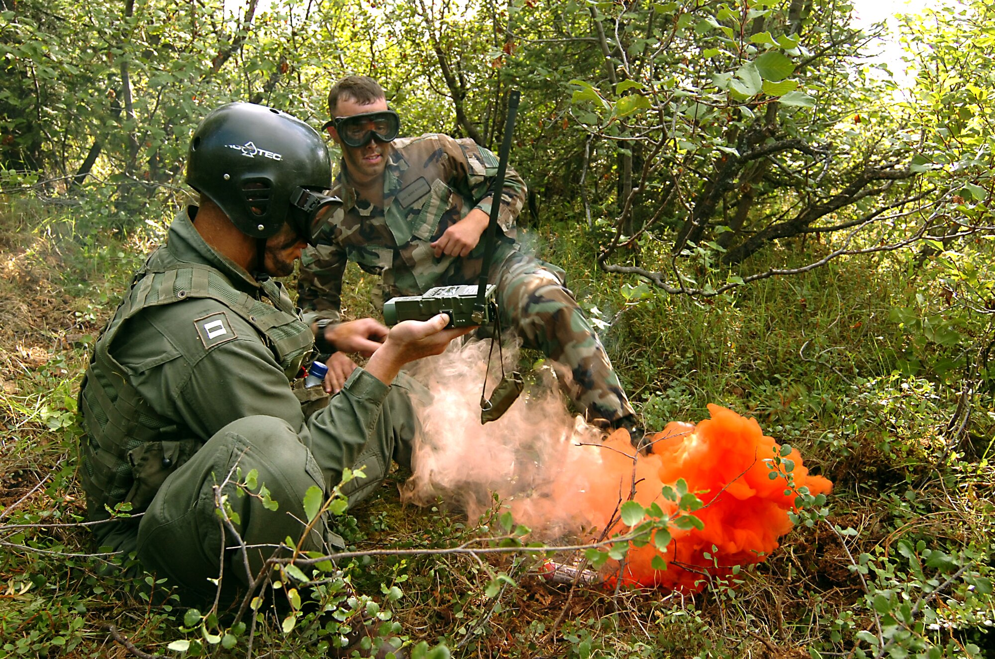 EIELSON AIR FORCE BASE, Alaska -- Navy Lieutenant Caleb Hogg communicates with an HH-60 Pave Hawk immediately after setting off a smoke flare canister to signal his position during a combat-search-and-rescue training scenario at Red Flag-Alaska. Staff Sgt. Marc Richard, a Survival, Evasion, Resistance and Escape specialist with the 353rd Combat Training Squadron, oversees the training exercise. The multinational training a Red Flag-Alaska helps to build familiarity between the allies in the Global War on Terror. (U.S. Air Force photo by Master Sgt. Brandt Smith)
