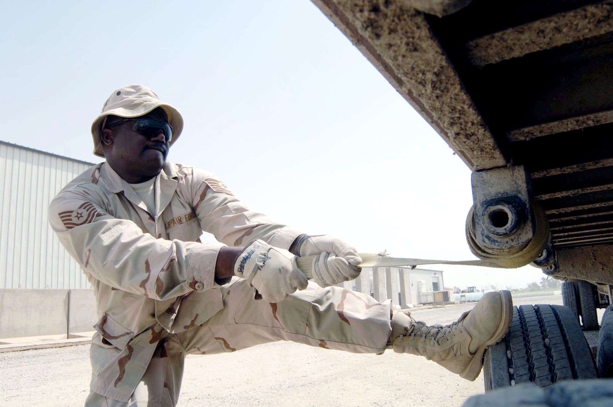 Tech. Sgt. Raymond Ford attempts to loosen a tie-down strap used for securing palletized water for transport from Camp Liberty to Sather Air Base, Iraq. Sergeant Ford is assigned to the 447th Expeditionary Logistics Readiness Squadron. (U.S. Air Force photo/Tech. Sgt. Russell Wicke) 
