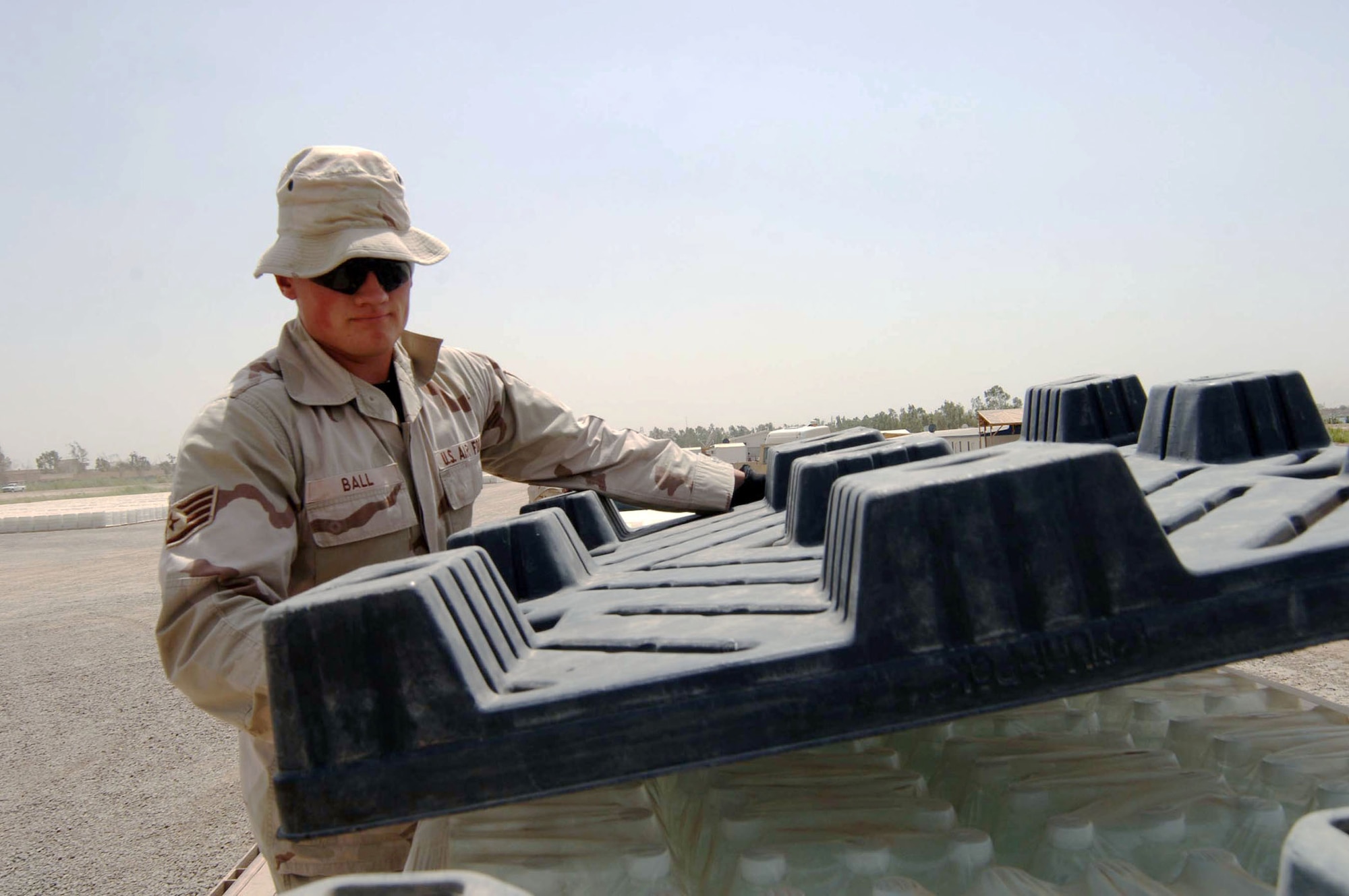Staff Sgt. Richard Ball covers palletized water before strapping it to a flat-bed truck at Camp Liberty in Iraq. The water will be trucked to Sather Air Base, Iraq, for distribution. Sergeant Ball is assigned to the 447th Expeditionary Logistics Readiness Squadron. (U.S. Air Force photo/Tech. Sgt. Russell Wicke) 
