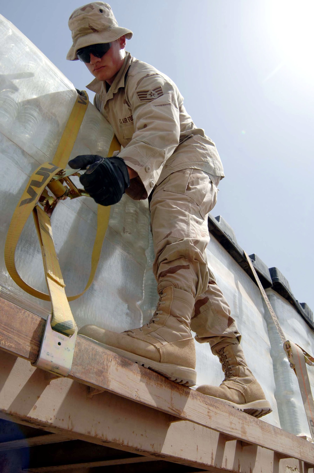Staff Sgt. Richard Ball tightens a tie-down strap used to secure palletized water for transport from Camp Liberty to Sather Air Base, Iraq. Sergeant Ball is assigned to the 447th Expeditionary Logistics Readiness Squadron. (U.S. Air Force photo/Tech. Sgt. Russell Wicke) 
