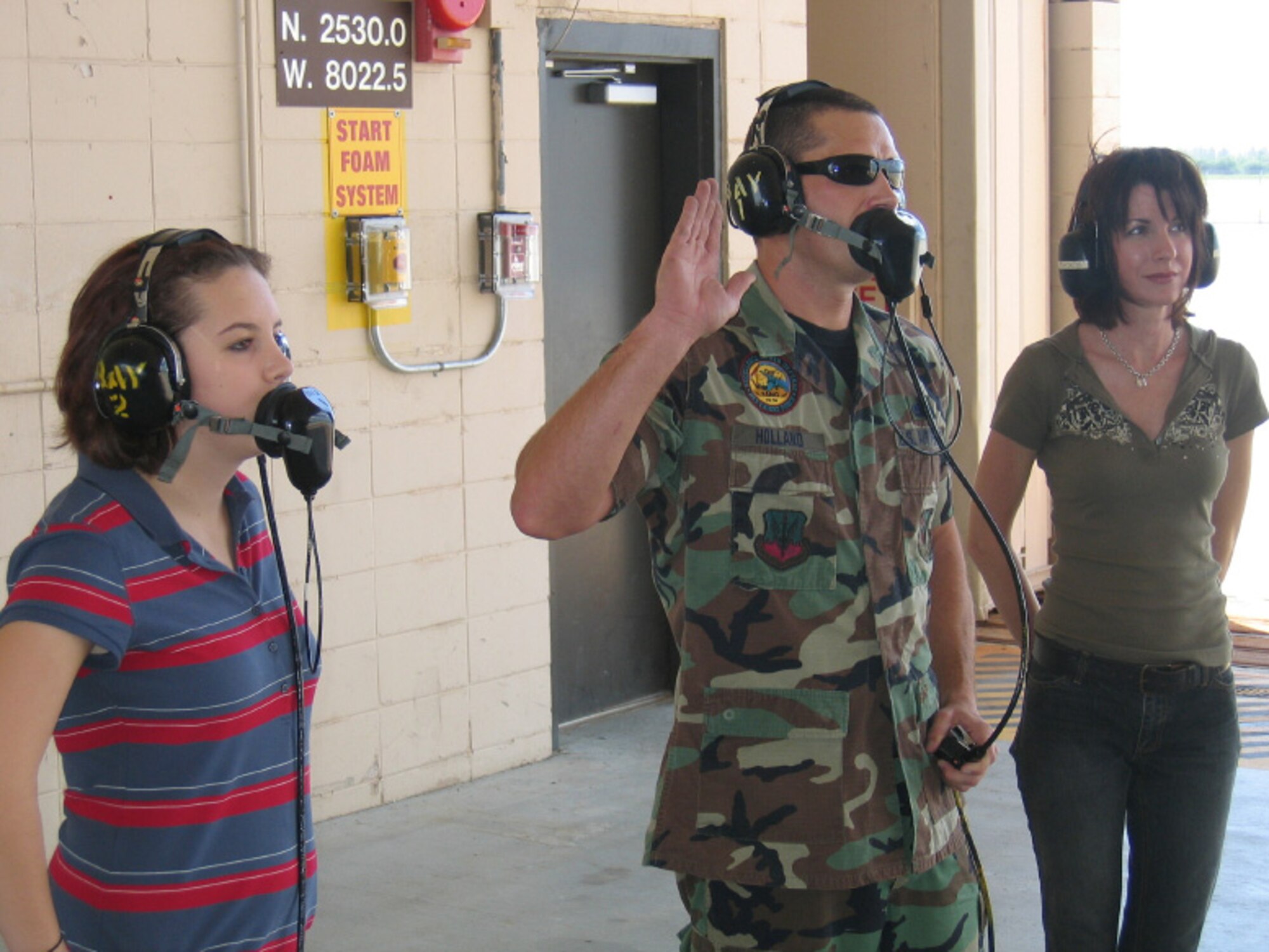 (L-R) Christian Holland watches as her father, Technical Sgt. Gary W. Holland, recites the oath of enlistment with his wife, Shelley, by his side.  (USAF photo/Major Cory W. "Trap" Bower)