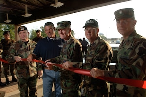 Col. Paul R. Ackerley, 316th Wing commander, cuts a red ribbon stretched across the identification check point, marking the opening of the new Main Gate as Col. Jeffery Bateman, 316th Security Forces Squadron commander, left, Curt Brinkley, Weston Solutions, Inc. Main and Virginia Gate construction superintendant, Col. Stewart S. Price, 316th Mission Support Group commander and Lt. Col. Brian P. Duffy, 316th Civil Engineer Squadron commander, hold the ribbon steady. (U.S. Air Force/SSgt Tanika Belfield)
