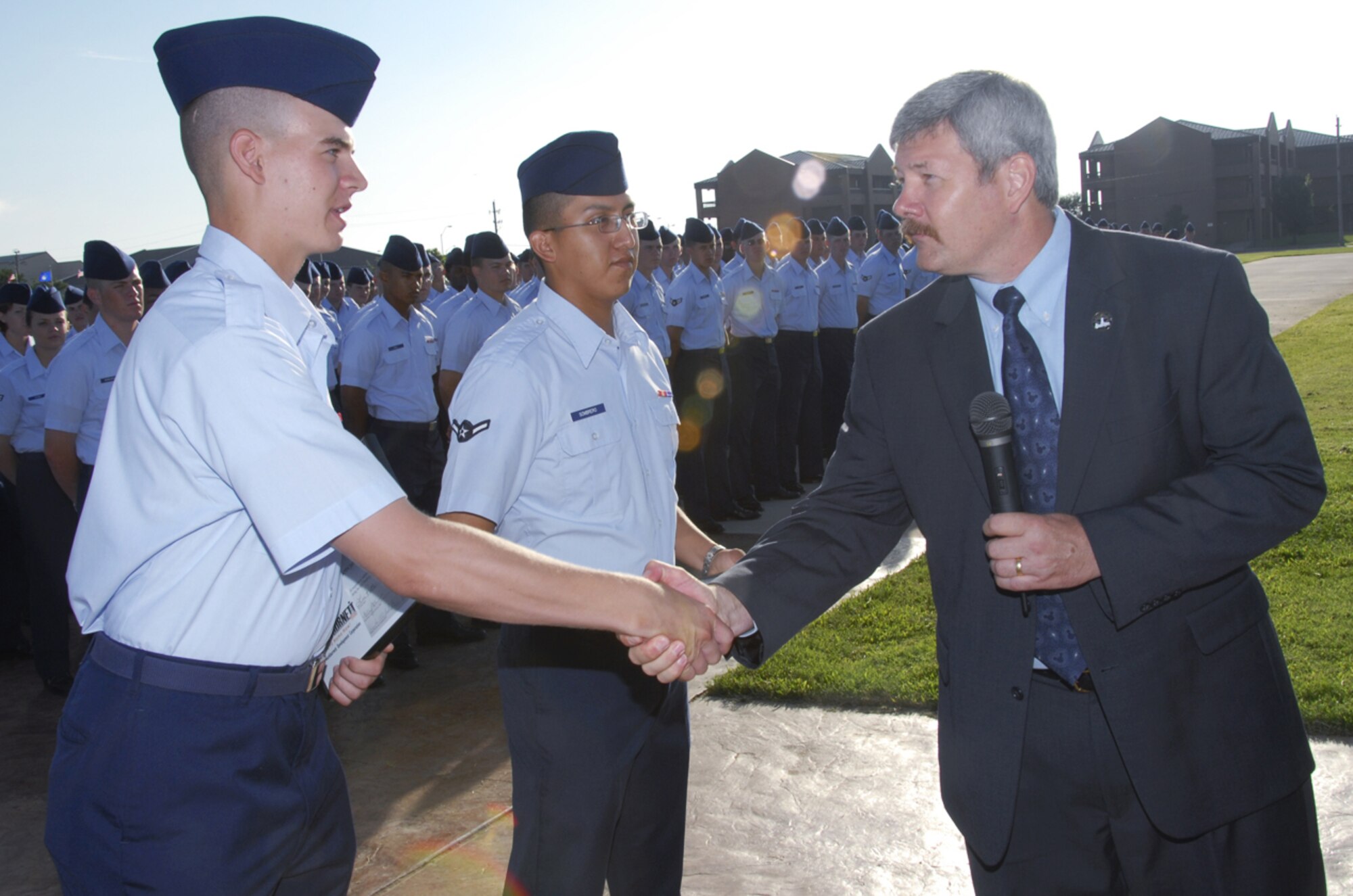 Mike Tugman, right, the mayor pro-tem for the City of Burkburnett, congratulates Airman Jacob Henkensiefken, right, after presenting letters of appreciation July 20 to him and Airman Robert Sombrero, center. The 361st Training Squadron Airmen volunteered to assist in the clean up following the Fourth of July celebration in Burkburnett. (U.S. Air Force photo/Sandy Wassenmiller)