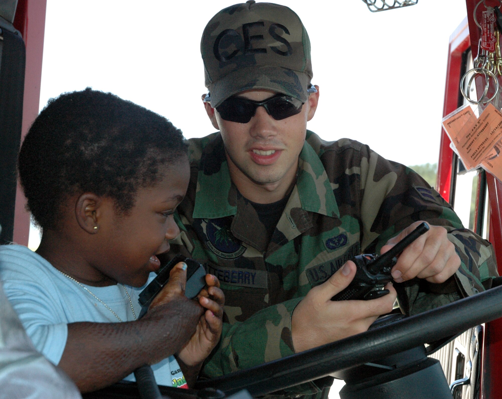 Dajah Potter, 7, conducts a radio control check from one of Tyndall’s fire trucks back to the command center at the fire station with the help of Airman 1st Class Bobby Atteberry, 325th Civil Engineer Squadron fire fighter.  The girl was one of 57 recent burn survivors that came to spend lunch with personnel from the base fire department today as part of the Children’s Burn Camp of North Florida, Inc., Camp Amigo program.  It is the second year the camp, that spends a week at Cape San Blas, stopped by Bonita Bay to picnic along the way to visiting local area attractions.
