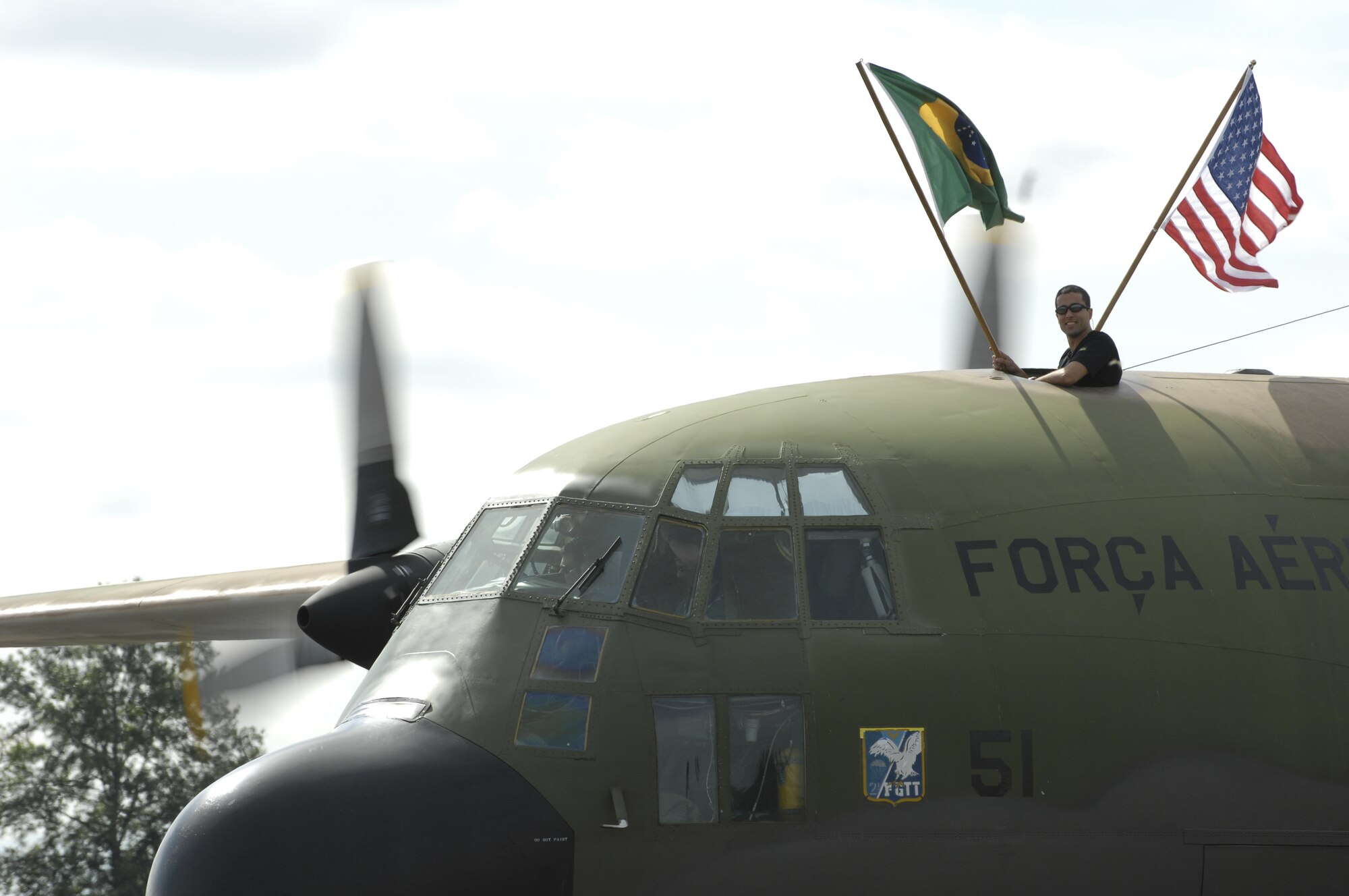 A Brazilian Air Force member proudly shows off the Brazilian flag while their C-130 aircraft taxis down the flight line at McChord Air Force Base, Wash., July 16, 2007, after arriving for Air Mobility Rodeo 2007. Rodeo 2007, hosted by Air Mobility Command, is a readiness competition of U.S. and international mobility air forces. It focuses on improving war fighting capabilities and support of the Global War on Terrorism. (U.S. Air Force photo/Senior Airman Jacqueline Kabluyen)