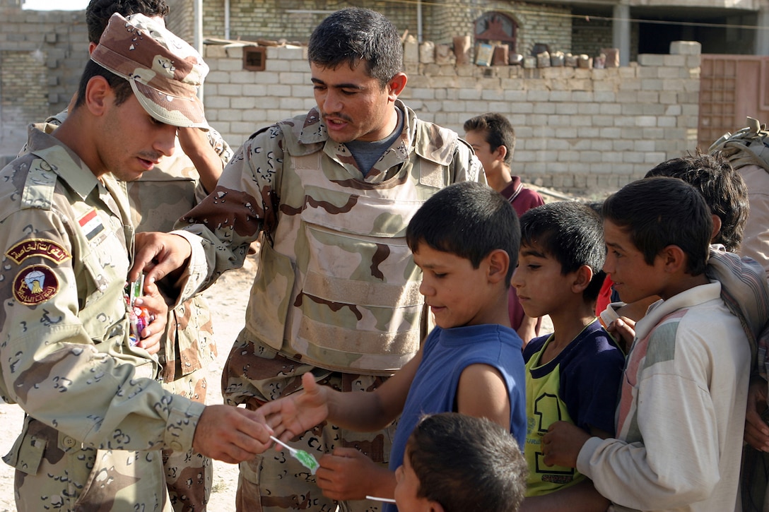 070721-M-1876J-DROP3—Iraqi Army soldiers take time to hand out candy to children of the poverty stricken neighborhood of Shuhada in southern Fallujah July 21. Handing out candy to the children was part of a civil assistance operation carried out by the combined efforts of Iraqi Army, Iraqi Police and U.S. Forces. (Photo by Pfc. Brian D. Jones)