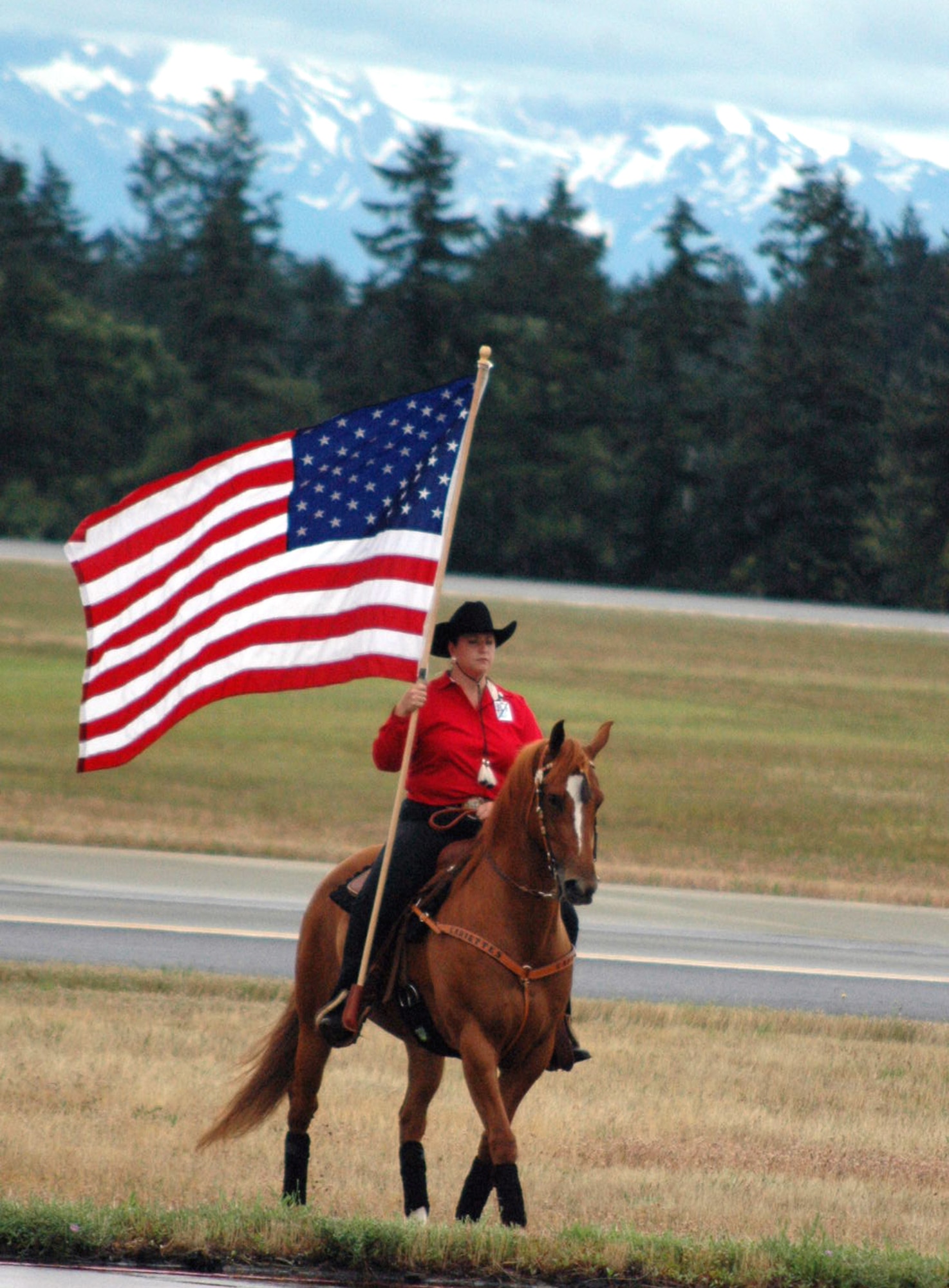 A horse-riding instructor carries the American flag during the opening ceremony for Air Mobility Rodeo July 22 at McChord Air Force Base, Wash. Rodeo, sponsored by Air Mobility Command, is a readiness competition for U.S. and international mobility air forces.  Besides numerous international teams and observers, there are also teams from across the Air Force, Air Force Reserve, Air National Guard and the U.S. Marine Corps. (U.S. Air Force photo/Tech. Sgt. Scott T. Sturkol)