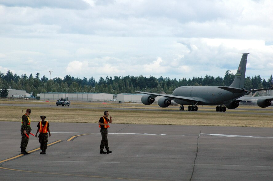Maintenance Airmen work on the flightline at McChord Air Force Base, Wash., while a KC-135R Stratotanker from Grand Forks AFB, N.D., taxis to a parking area during operations for Air Mobility Rodeo 2007, July 21.  Rodeo, sponsored by Air Mobility Command, is a readiness competition for U.S. and international mobility air forces. This competition focuses on improving world-wide mobility forces' professional core abilities. More than 40 teams and 2,500 people from the Air Force, and Air Force Reserve, as well as allied nations, are expected to participate. (U.S. Air Force Photo/Tech. Sgt. Scott T. Sturkol)
