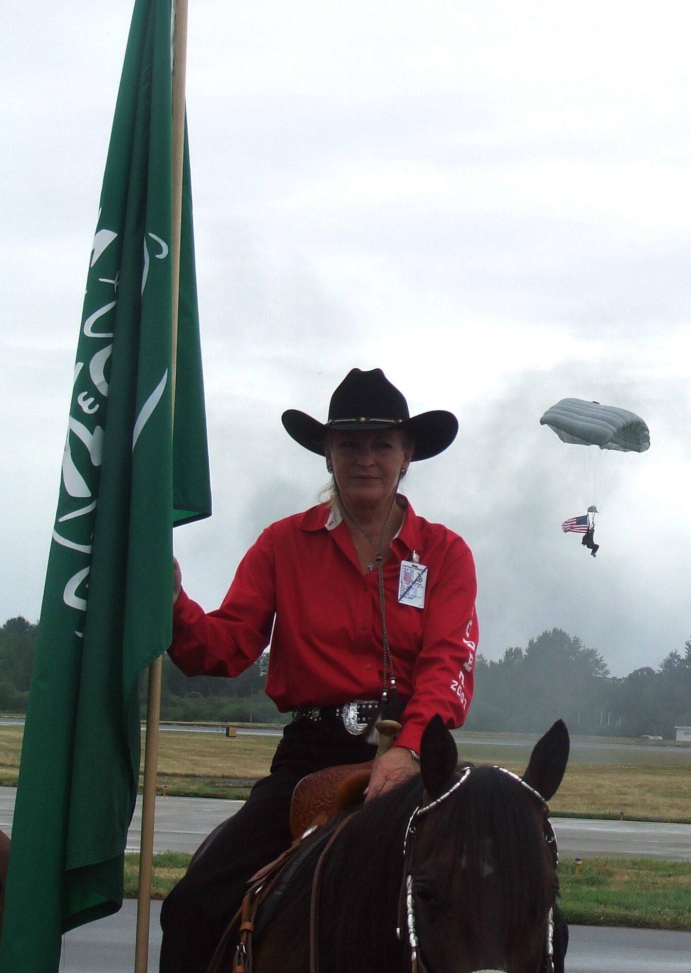 A horse-riding instructor carries the Saudi Arabia flag while Chief Master Sgt. Michael Breeded, 22nd Special Tactics Squadron, parachutes in with the American flag during the opening ceremony for Air Mobility Rodeo July 22, at McChord Air Force Base, Wash. Rodeo, sponsored by Air Mobility Command, is a readiness for U.S. and international mobility air forces.  Besides numerous international teams and observers, there are also teams from across the Air Force, Air Force Reserve, Air National Guard, and the U.S. Marine Corps. (U.S. Air Force Photo/Tech. Sgt. Scott T. Sturkol)