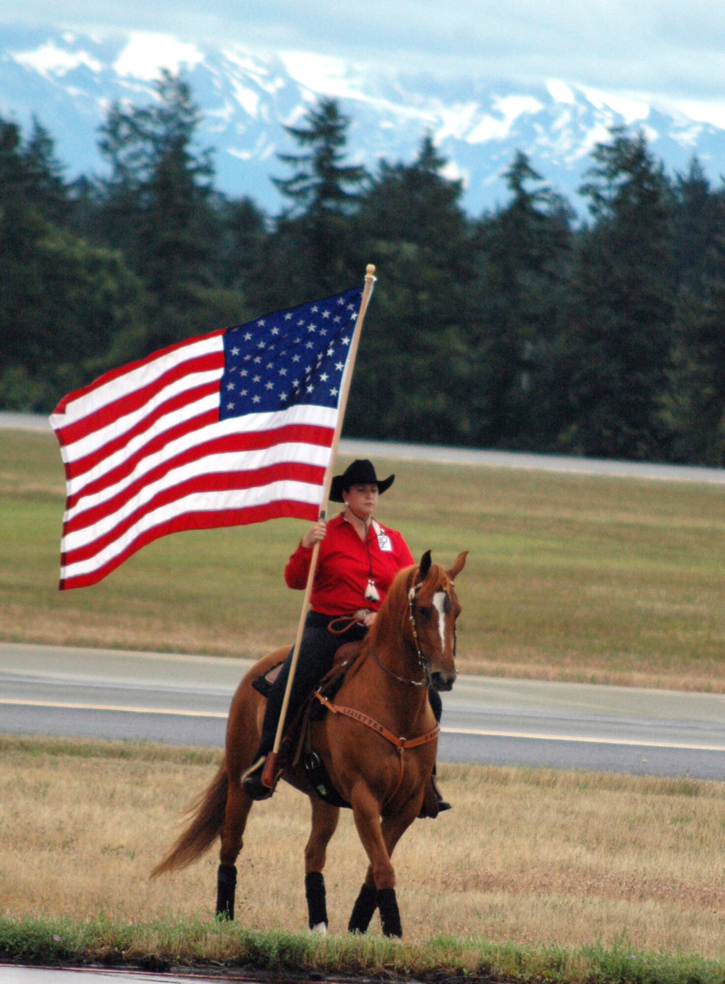 A horse-riding instructor carries in the American flag during the opening ceremony for Air Mobility Rodeo July 22 at McChord Air Force Base, Wash. Rodeo, sponsored by Air Mobility Command, is a readiness for U.S. and international mobility air forces.  Besides numerous international teams and observers, there are also teams from across the Air Force, Air Force Reserve, Air National Guard, and the U.S. Marine Corps. (U.S. Air Force Photo/Tech. Sgt. Scott T. Sturkol)