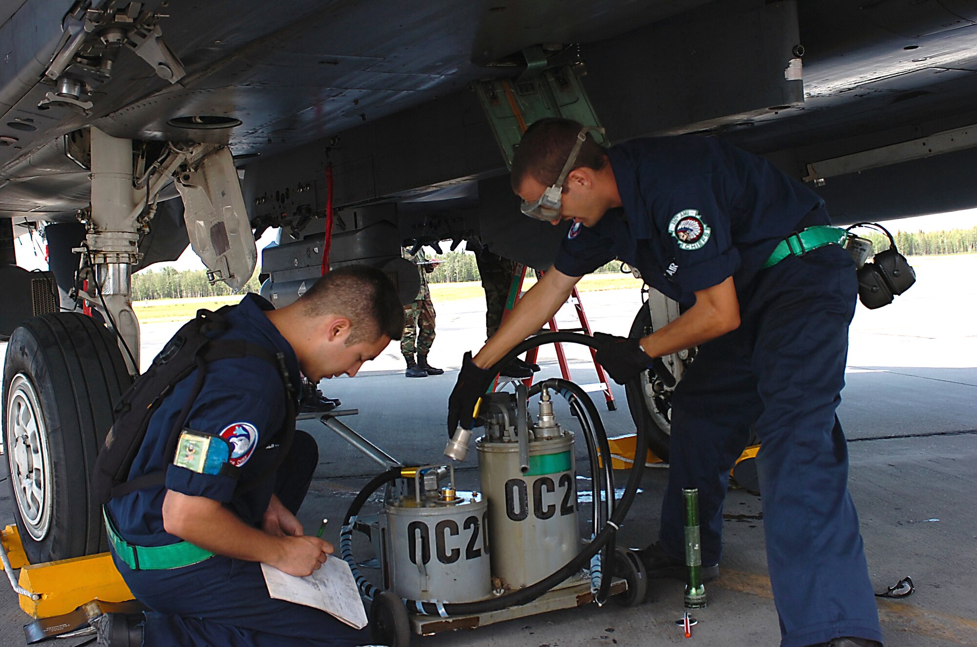 EIELSON AIR FORCE BASE, Alaska -- Staff Sgt. Steve Tolliffe (left) and Airman 1st Class Harrison McMillan, both crew chiefs with the 4th Aircraft Maintenance Squadron, service their aircraft's engine oil after a training sortie at Red Flag-Alaska, a multinational air combat exercise. Both Airmen are from Seymour Johnson AFB, N.C. (U.S. Air Force photo by Master Sgt. Brandt Smith)  
