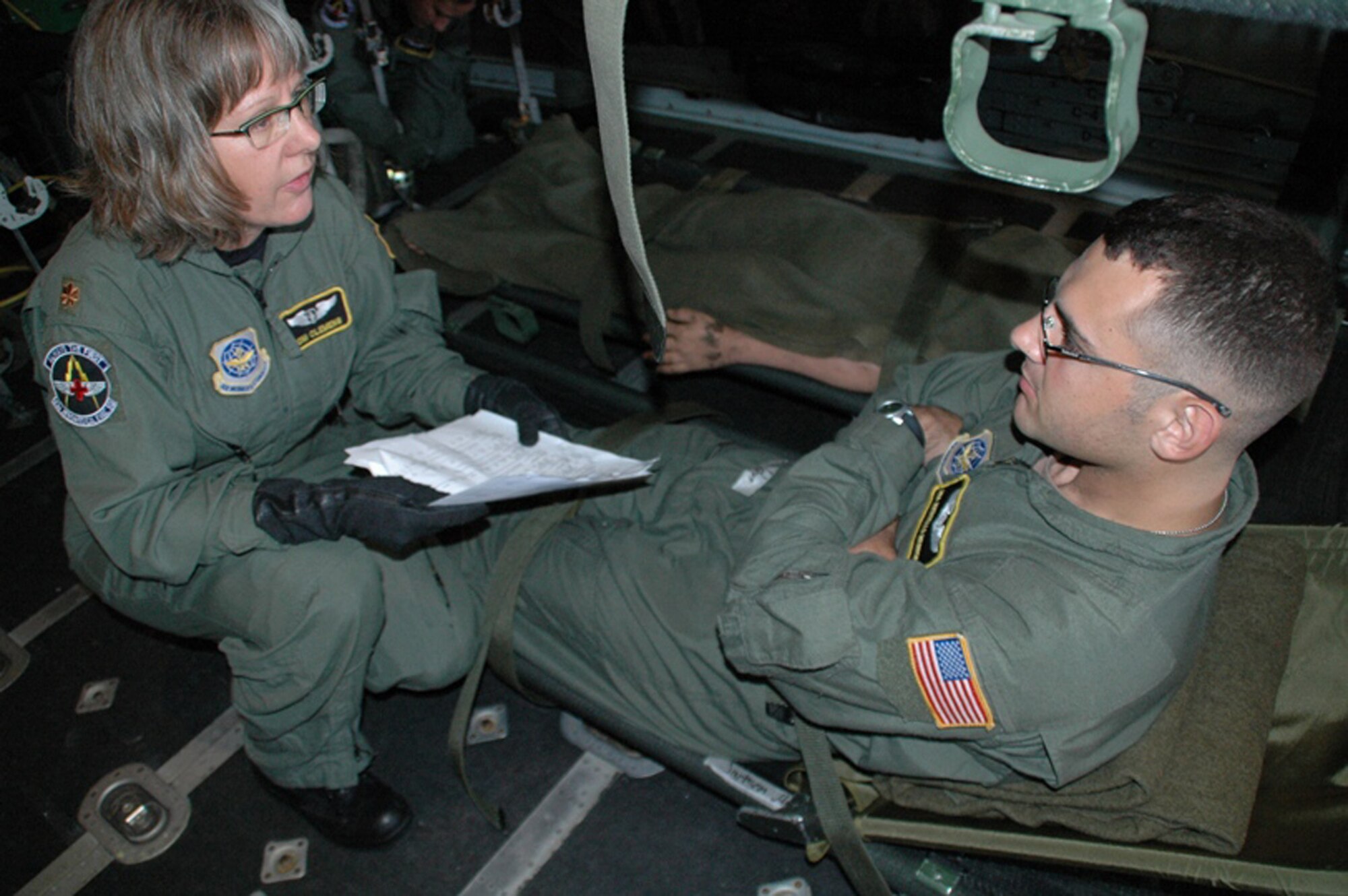 Maj. Joni Clemens assesses Senior Airman Joseph Morgan who was a "patient" during an aeromedical evacuation training mission July 19 that originated at Pope Air Force Base, N.C.  The mission provided the opportunity for the Reserve flying unit there to train with one of the active duty aeromedical evacuation units there.  Major Clemens, with the 43rd Aeromedical Evacuation Squadron at Pope Air Force Base, N.C., served as the medical crew director.  Airman Morgan also is with the 43rd AES.  The flight was one of the first operational missions for the Air Force Reserve Command's 440th Airlift Wing from its new location at Pope AFB.  The Reserve unit moved to North Carolina from Wisconsin in June. (U.S. Air Force photo/Maj. Ann Knabe)
