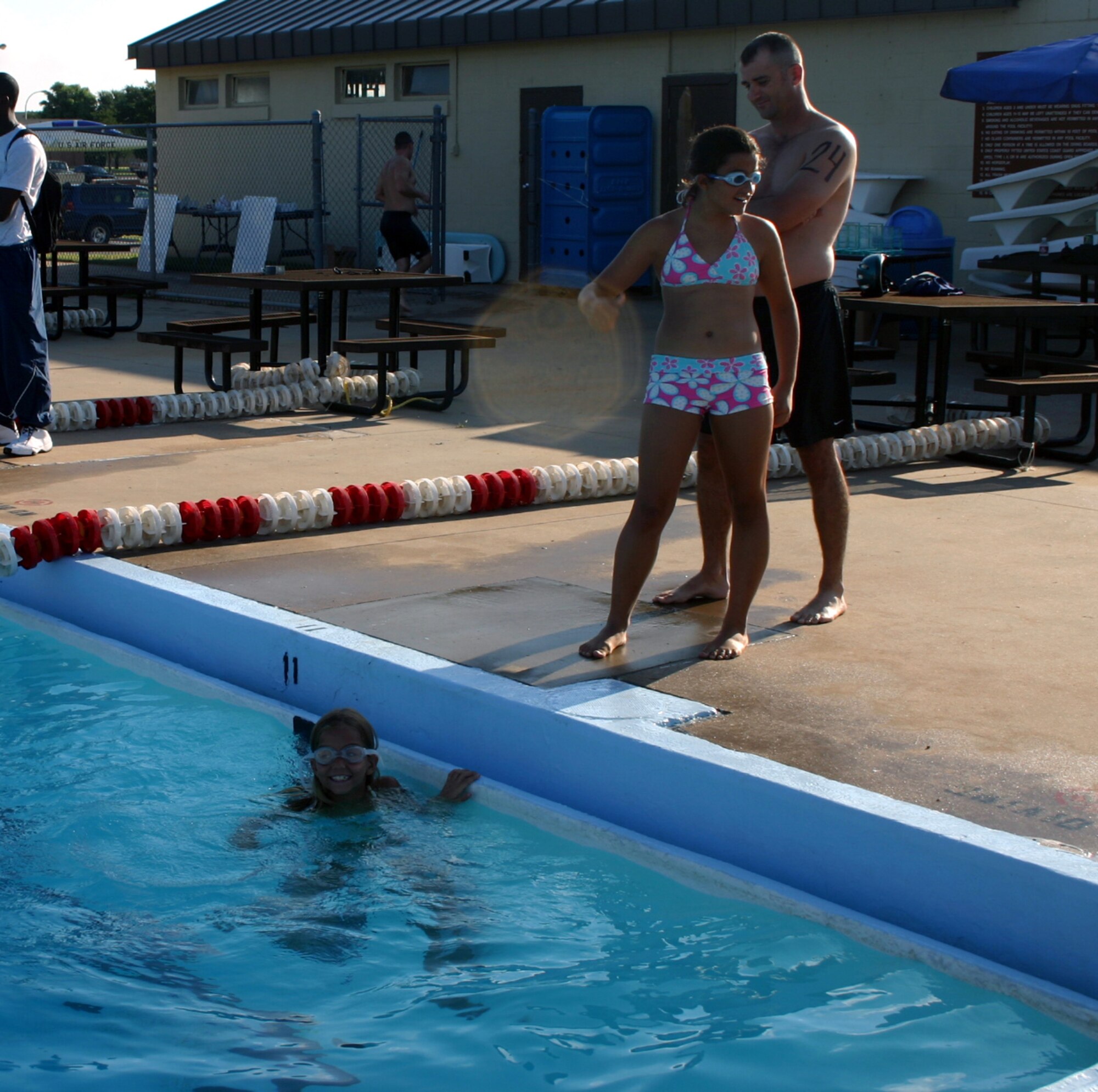 Katie Alfred prepares to swim her laps as sister Fiama Alfred and father Mike Young look on.  Katie won first place in the female youth division of the 82nd Services Squadron's mini-triathalon July 21. (U.S. Air Force photo/Staff Sgt. Tonnette Thompson)