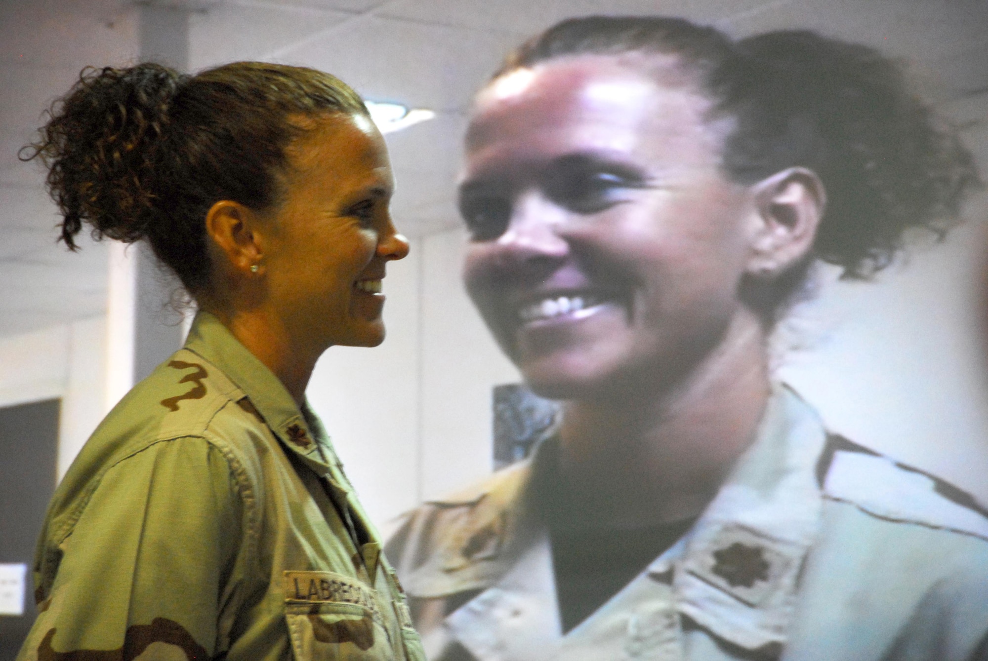 SOUTHWEST ASIA -- Maj. Eileen LaBrecque, smiles as she watches her family on the video teleconferencing screen from the Combined Air and Space Operations Center here.  The major used the VTC to administer the oath of enlistment to her husband, Craig, who pinned on captain during the promotion ceremony July 16.  (U.S. Air Force photo by Tech Sgt. Scott Moorman.)