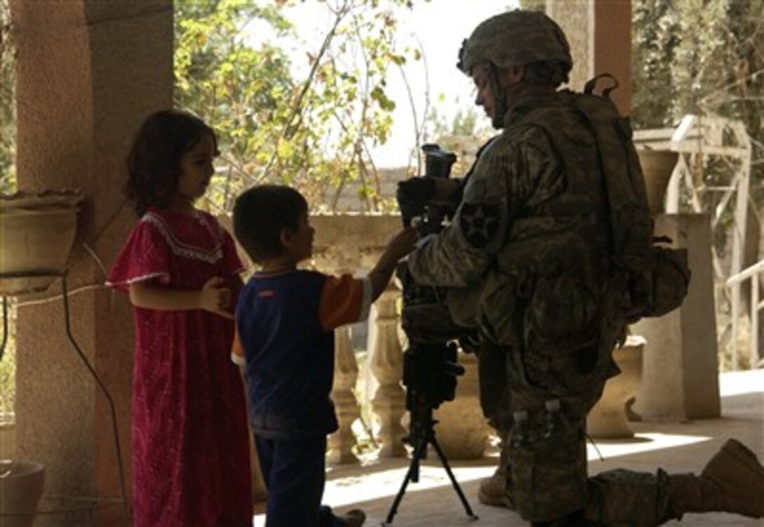 U.S. Army Pfc. Scott Hall, Bravo Company, 1st Battalion, 23rd Infantry Regiment, speaks with children outside a secured house in Baqubah, Iraq, July 21, 2007. 