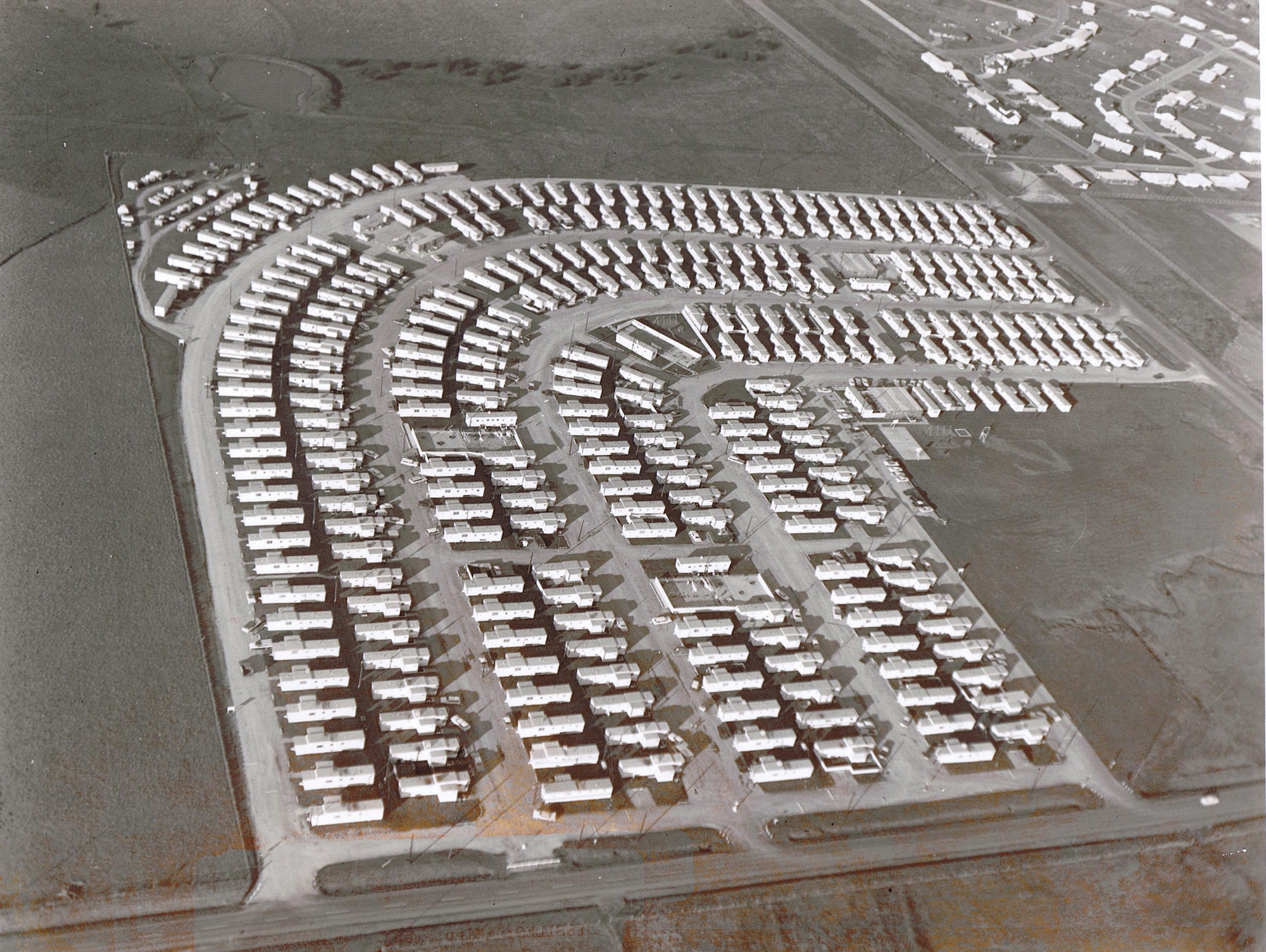 WHITEMAN AIR FORCE BASE, Mo. -- An overhead view of temporary housing built near Whiteman for the firm of Morrison, Hardeman, Perrini, and Level, which received the prime contract for construction of hardened, underground launch facilities and 15 launch control centers Jan. 17, 1962. In June 1961, the Department of Defense chose Whiteman to host the fourth Minuteman ICBM wing. The construction project called for the excavation of 867,000 cubic yards of earth and rock. The contractors used 168,000 yards of concrete, 25,355 tons of reinforcing steel and 15,120 tons of structural steel. In addition, the project called for the installation of a vast underground intersite cable network. If laid end to end in a straight line, this cable would stretch from Whiteman to 100 miles beyond Los Angeles. Construction of the complex was officially completed in June 1964. (U.S. Air Force photo) 
