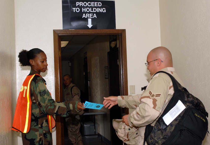 DYESS AIR FORCE BASE, Texas -- Senior Airman Danielle Sharpe, 7th Equipment Maintenance Squadron, hands out boarding passes before the 7th Bomb Wing deployment July 20. (U.S. Air Force photo/Senior Airman Courtney Garrard)