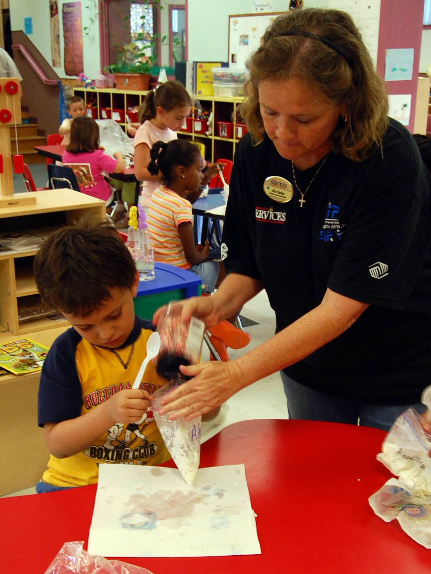 LAUGHLIN AIR FORCE BASE, Texas - Mrs. Alice Harlan, Youth Center staff member, pours sprinkles into Alex Pena's, son of Mr. Viviano and Mrs. Sabrina Pena, bag of ice cream in the Science Adventure camp at Laughlin's youth center. (U.S. Air Force photo by Airman Sara Csurilla)