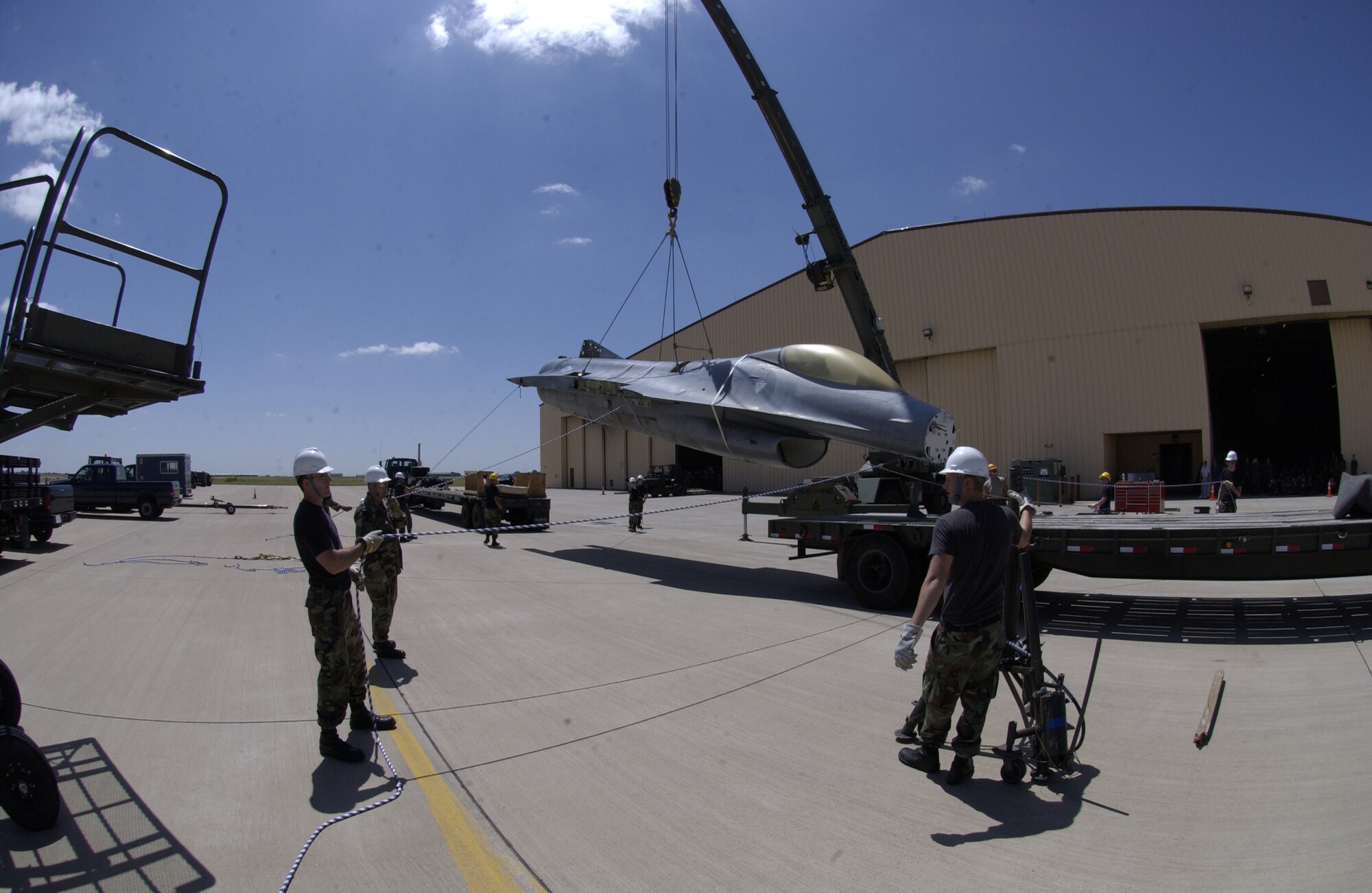 After lifting the fuselage of an F-16 off a trailer bed, Airmen steady it to be moved onto the bed of the truck in the background. The F-16, which was originally from Sheppard Air Force Base, Texas, will become a static display at the air park near the main gate. (U.S. Air Force photo by Airman Elliott Sprehe)