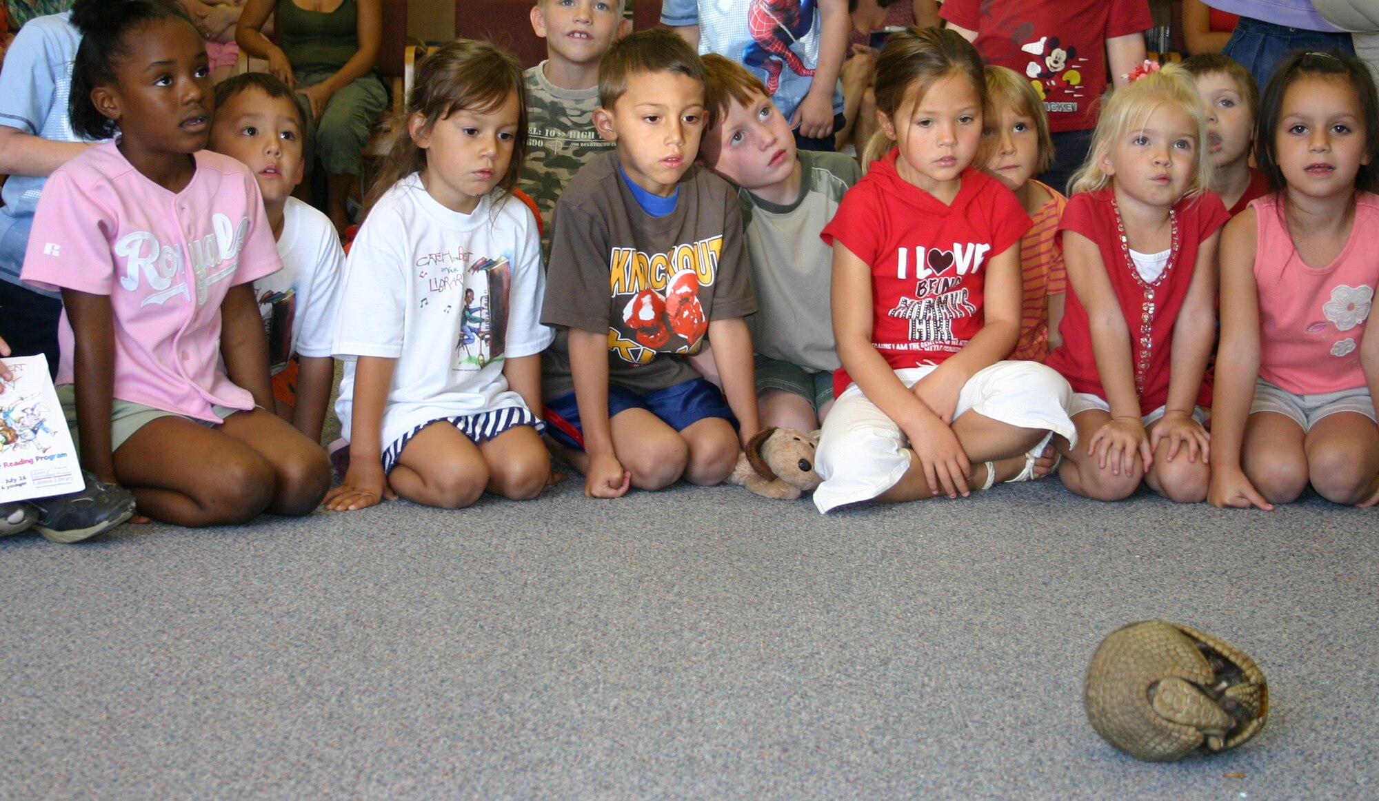 Children from around base wait for an armadillo to come out of its shell at the library here June 19. The Albuquerque Zoo brought out reptiles, amphibians, birds and mammals as part of the "Catch the Beat" program at the library. (U.S. Air Force photo by Airman Elliott Sprehe)