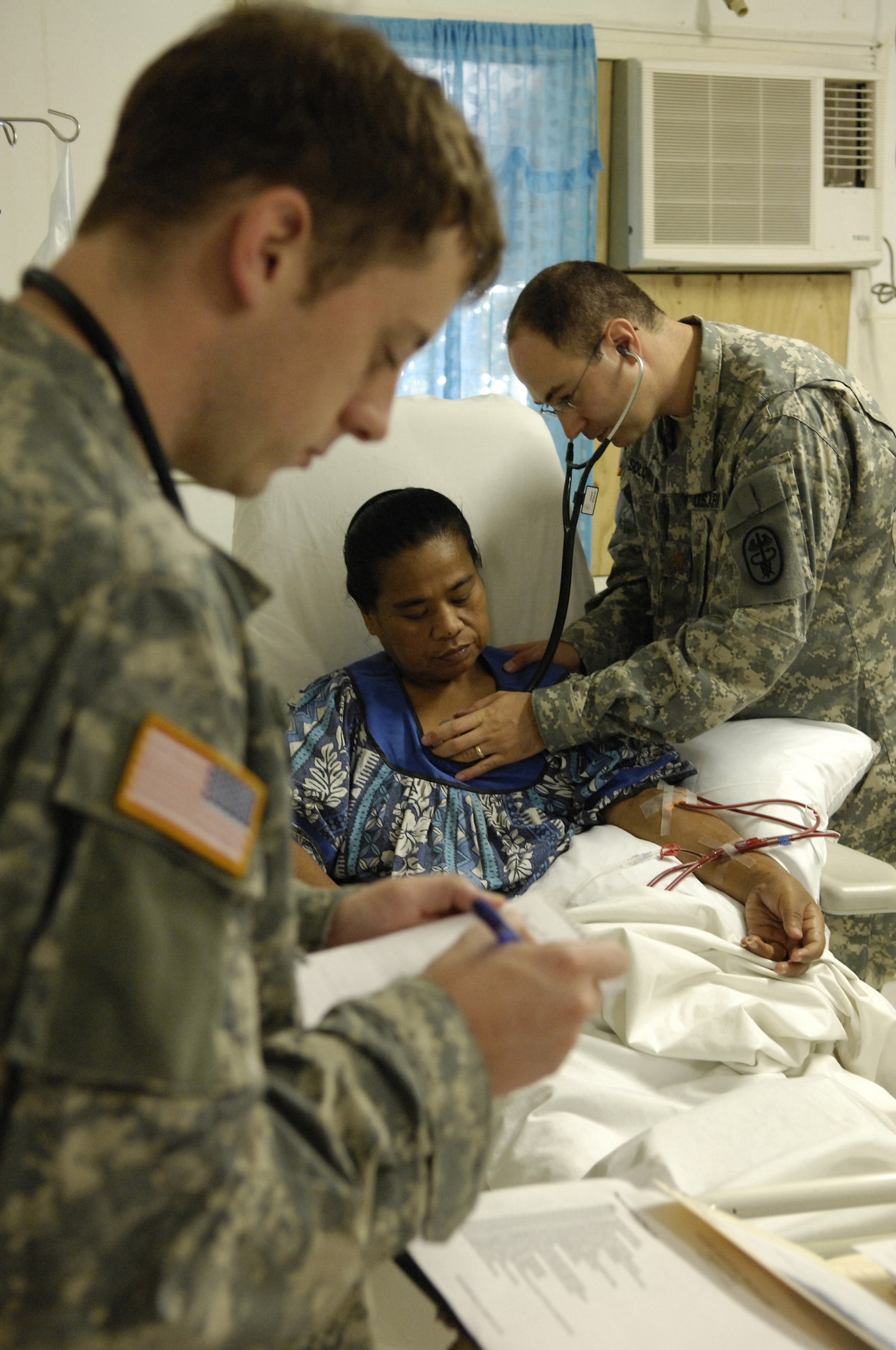 Dr. (Capt.) Evan Brown writes suggested medication adjustments while Dr. (Maj.) Noah Solomon listens to a dialysis patient's heartbeat at Nauru General Hospital July 23. Dr. Brown and Dr. Solomon are part of a 12-person joint force team from U.S. Pacific Command providing medical assistance and training on the island of Nauru. (U.S. Air Force photo by Tech. Sgt. Chris Vadnais)